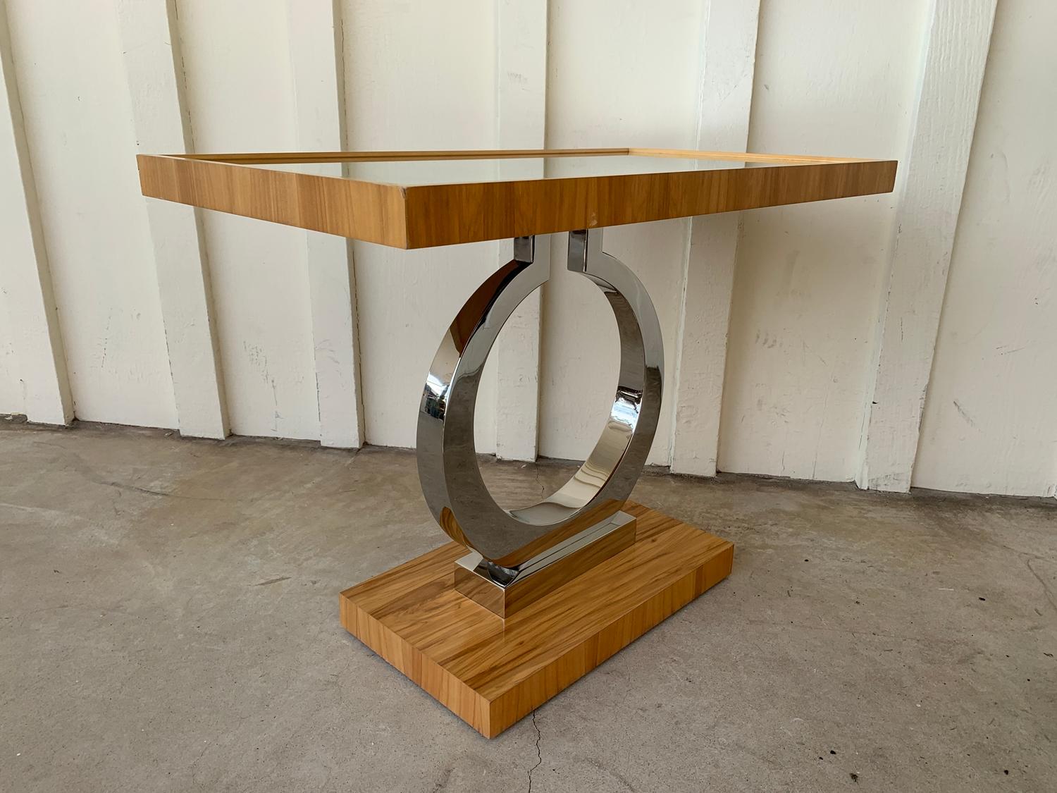 An inset mirrored tabletop with a gallery edge of satin walnut veneer rests on a polished stainless steel base and a satin walnut veneered base platform.

The table is in used condition with some of the veneer lifting specially around the