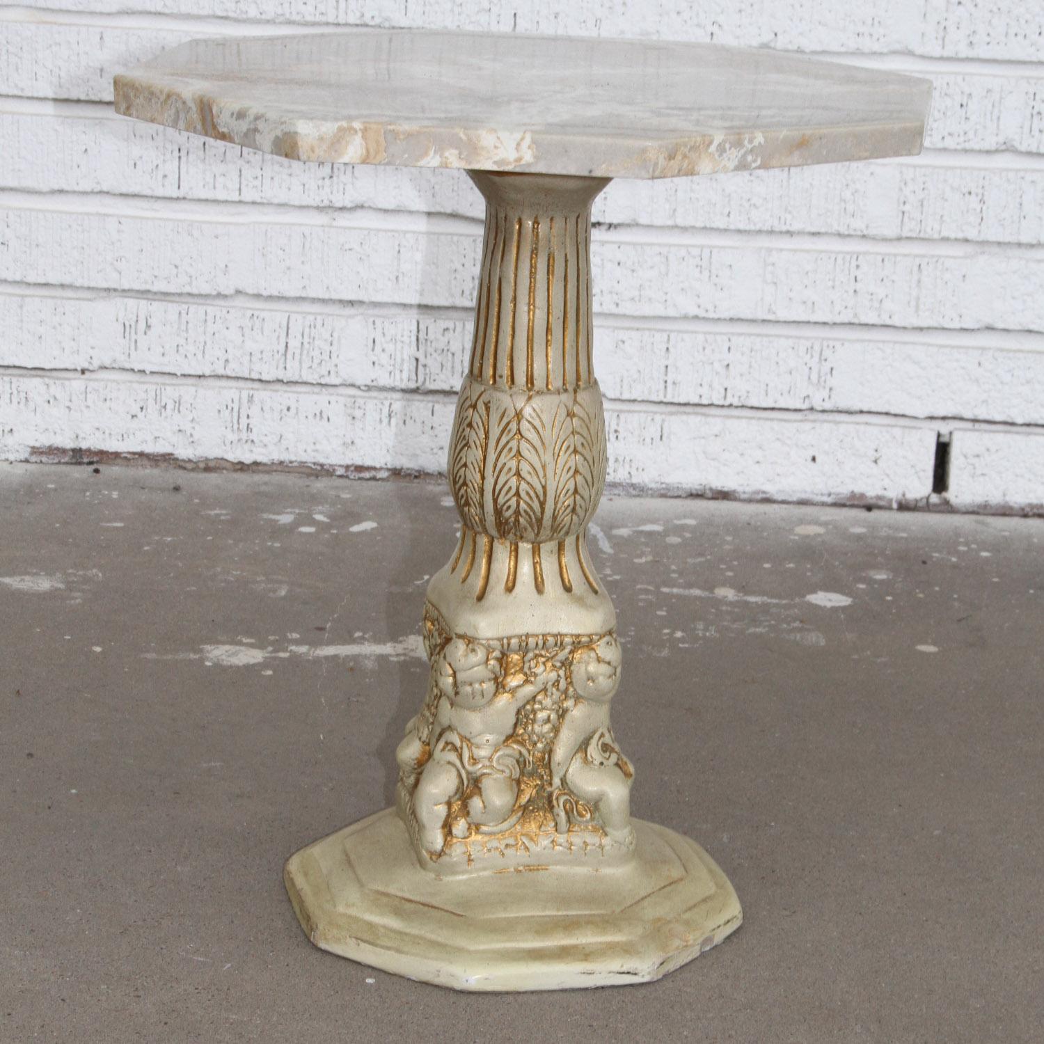 Side table with Octogan stone top 

Vintage side table in cast plaster with a faux marble stone top. The base has a carved design with cherubs around the base. Nice in a sheltered garden or porch.