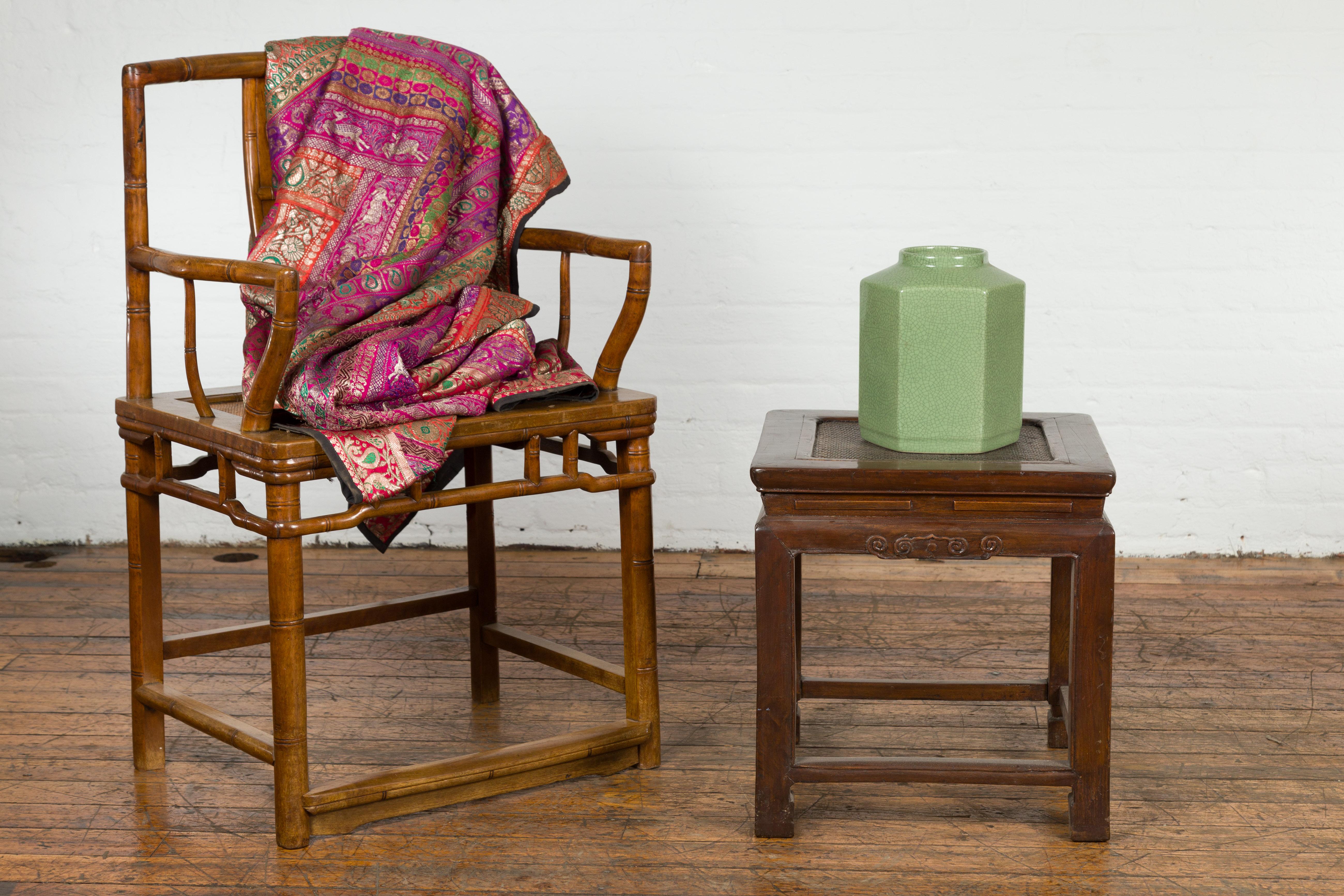 A late Qing Dynasty period wooden side table from the early 20th century with rattan inset top, scroll-carved apron and horsehoof feet. A poignant testament to craftsmanship from the late Qing Dynasty, this wooden side table is not just furniture