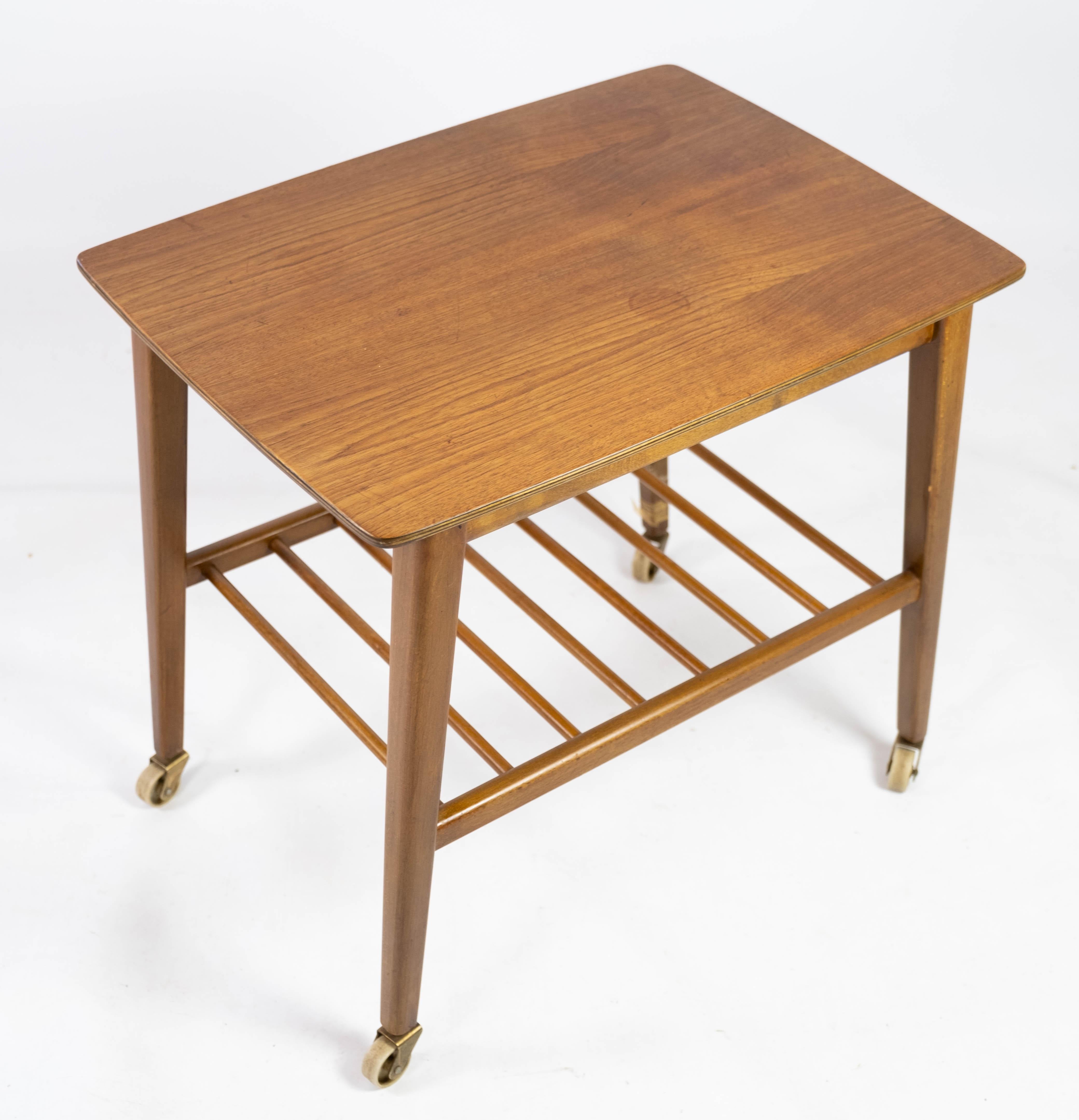 This Danish-designed side table from the 1960s combines functionality with sleek aesthetics. Crafted from teak, a wood renowned for its durability and warmth, this piece exudes timeless elegance.

Featuring a convenient shelf for extra storage and
