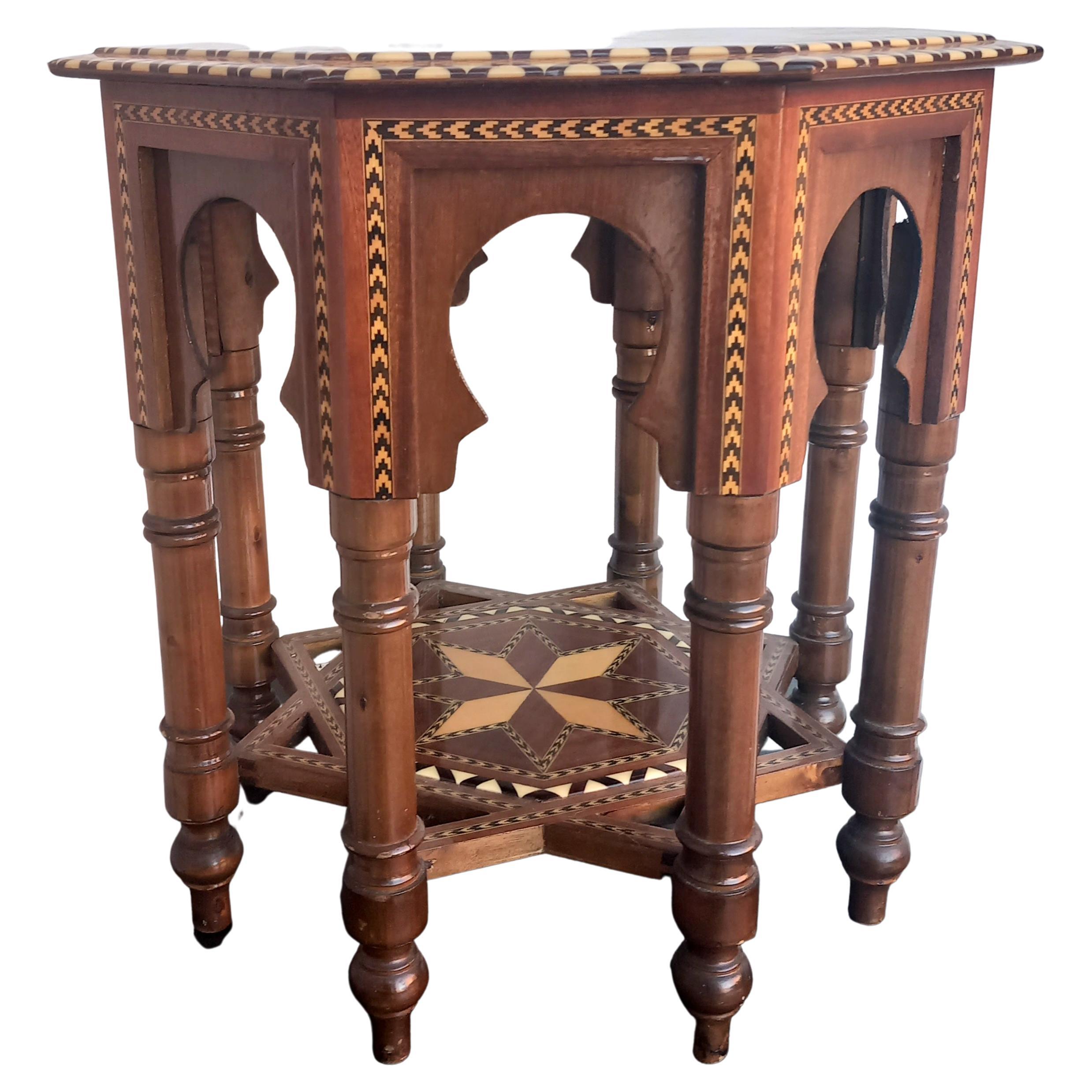 Table with very decorative Moorish inlays from the 20th century in a hexagonal shape
This leads to an arched frieze of temple design. The turned legs are supported by a star embedded in the base.  

These table are in good condition, central star