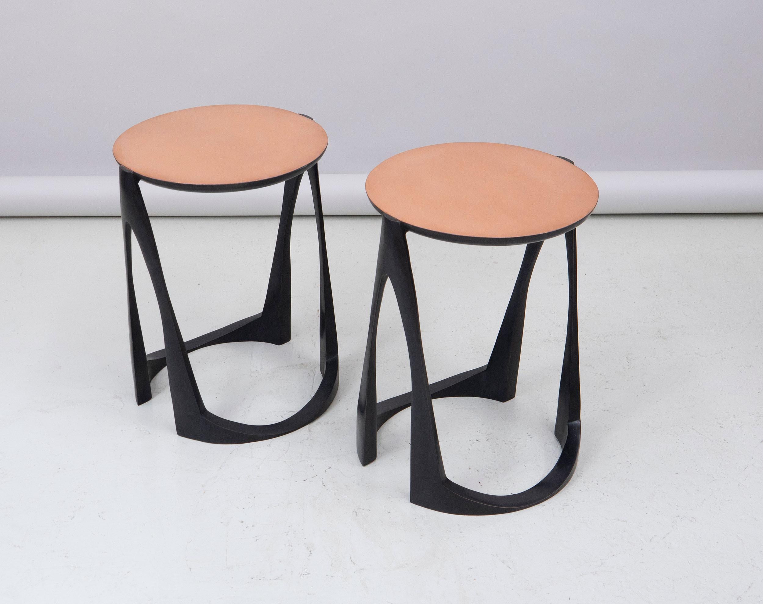 A pair of side tables in bronze with base in black patina and a top in natural bronze.