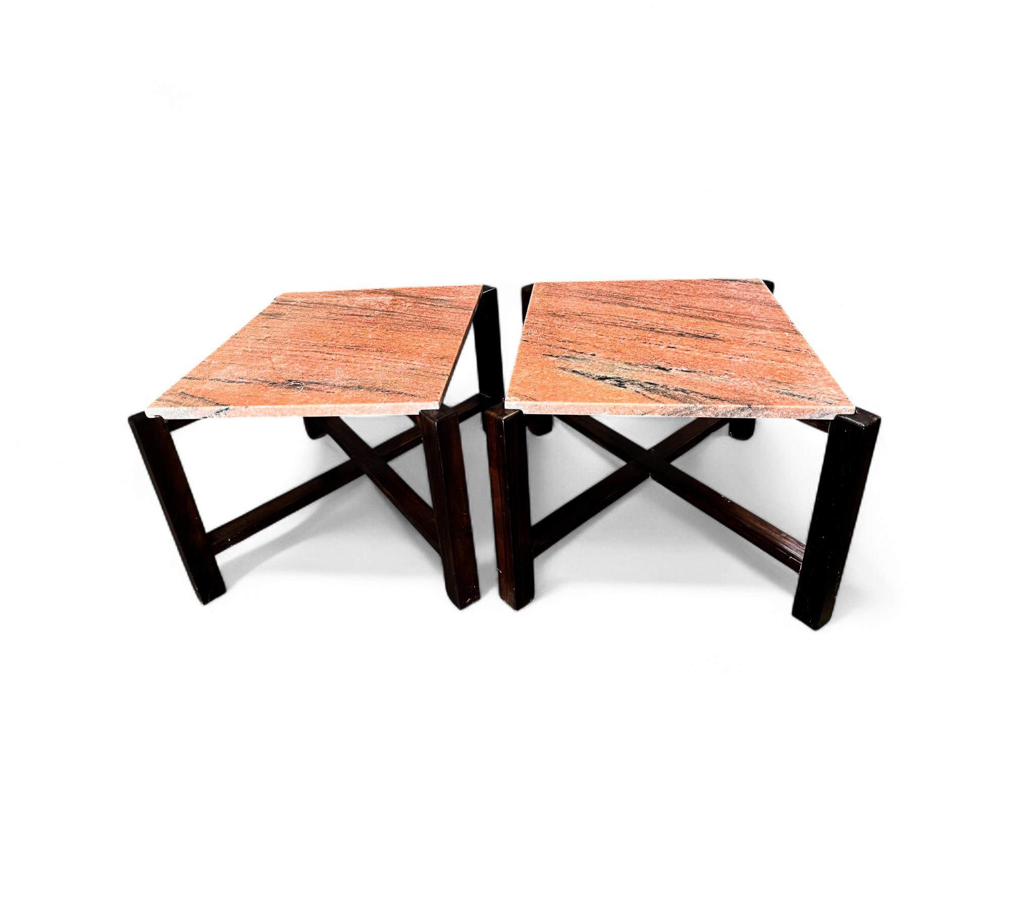 This elegant pair of side tables, crafted in Brazil in the 1960s, features a hardwood base with an X shape and four sturdy legs. The tops are adorned with stunning pink granite, which remains in excellent condition. The refinished wood highlights