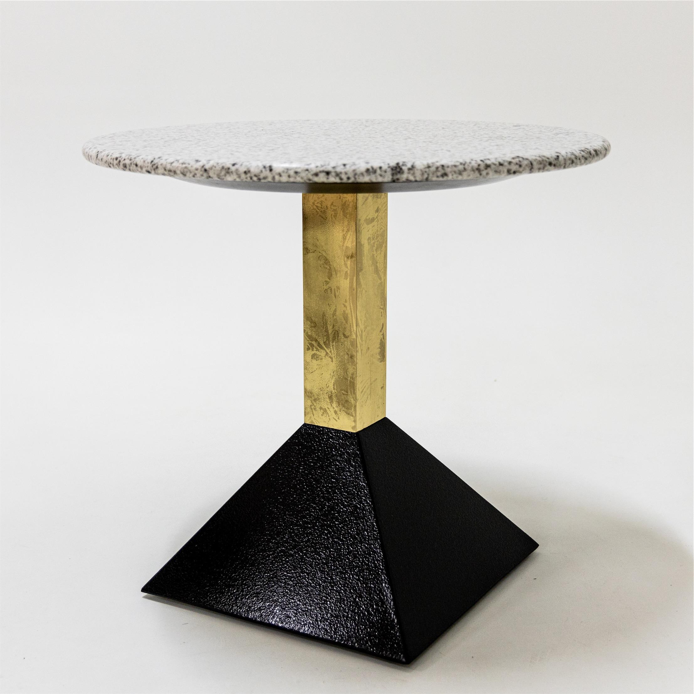 Pair of tables with round granite tops in white and pink respectively over a brass square shaft and black pyramidal base.