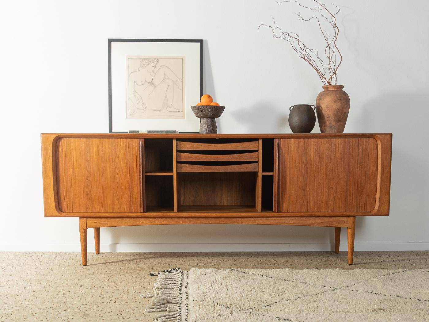 Sideboard 142 from the 1960s by Bernhard Pedersen & Søn. High-quality corpus in teak veneer with two tambour doors, three internal drawers, two shelves and tapered feet.

Quality Features:
 accomplished design: perfect proportions and visible