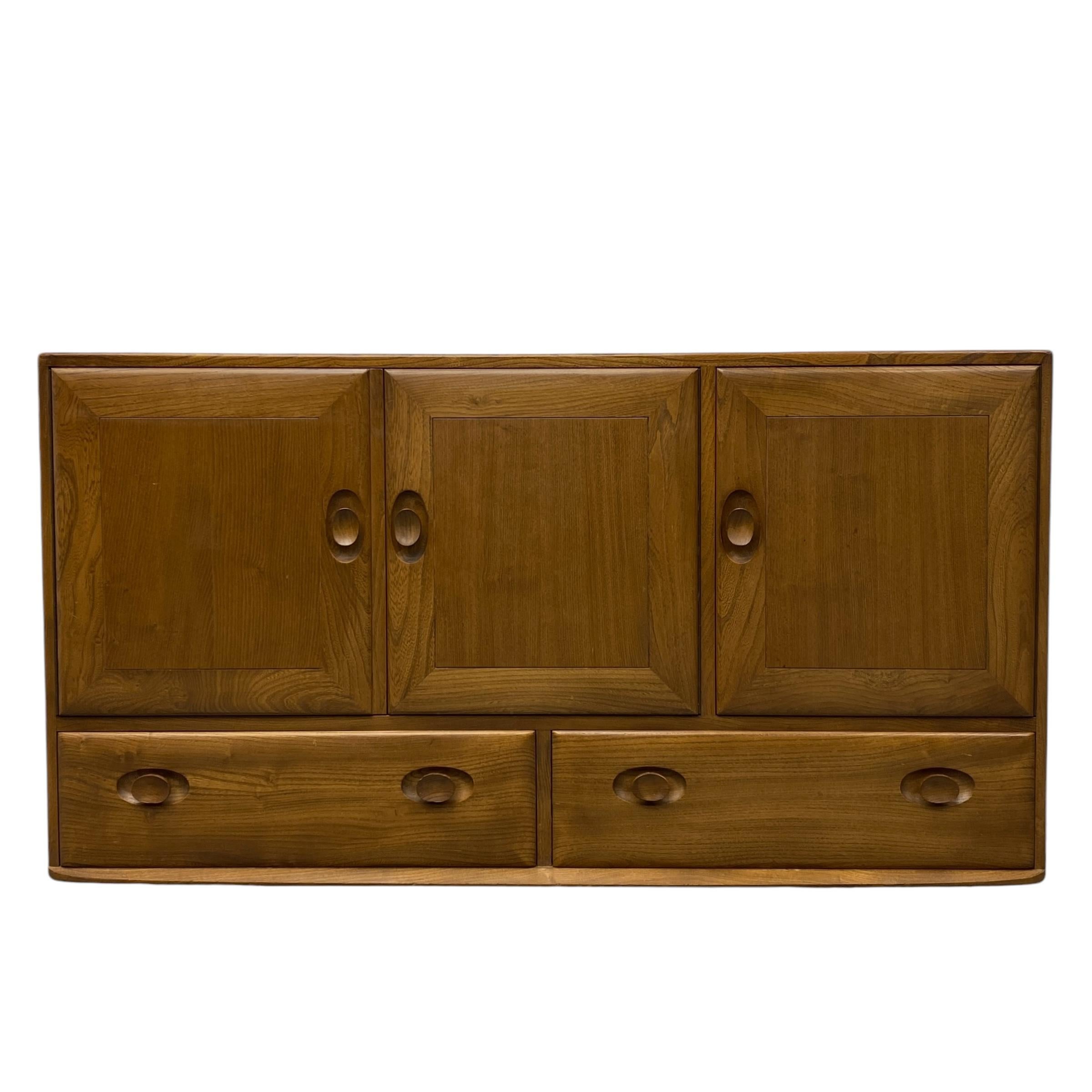 This medium sized English elm sideboard by Ercol, dating from the 1970s, is a British design classic from their ever-popular Windsor range. An expertly crafted piece of furniture with many of Ercol’s signature features on show, it epitomises the
