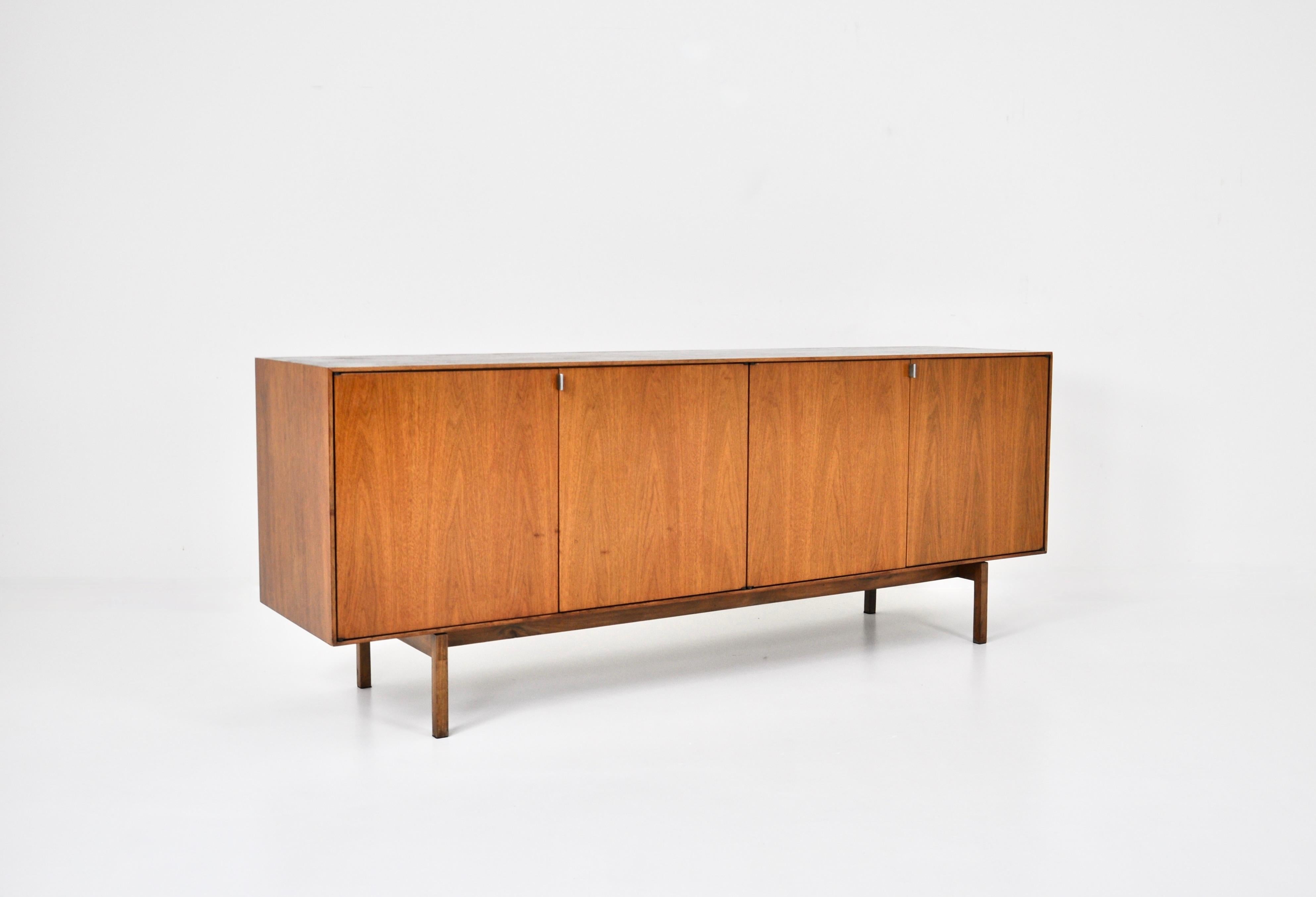 Wooden sideboard with 4 doors containing 2 drawers, 2 shelves and a large shelf by Florence Knoll. The handles are in metal. Wear due to time and age of the sideboard.