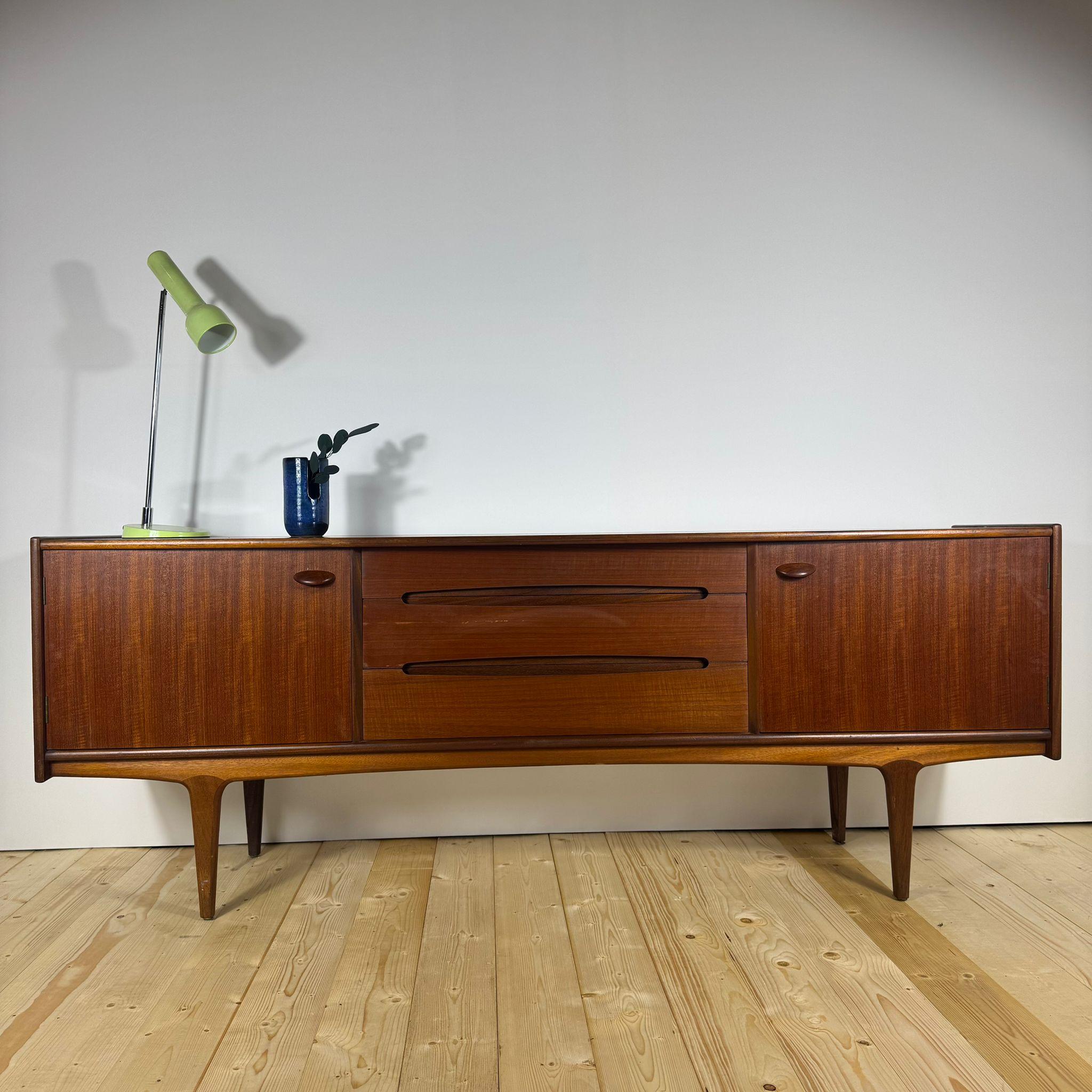 Questa credenza danese degli anni '60 è un capolavoro del design scandinavo che porta l'eleganza minimalista direttamente nel tuo spazio. Realizzato in teak, linee pulite e proporzioni armoniose tipiche dell'epoca d'oro del design nordico. Le ante