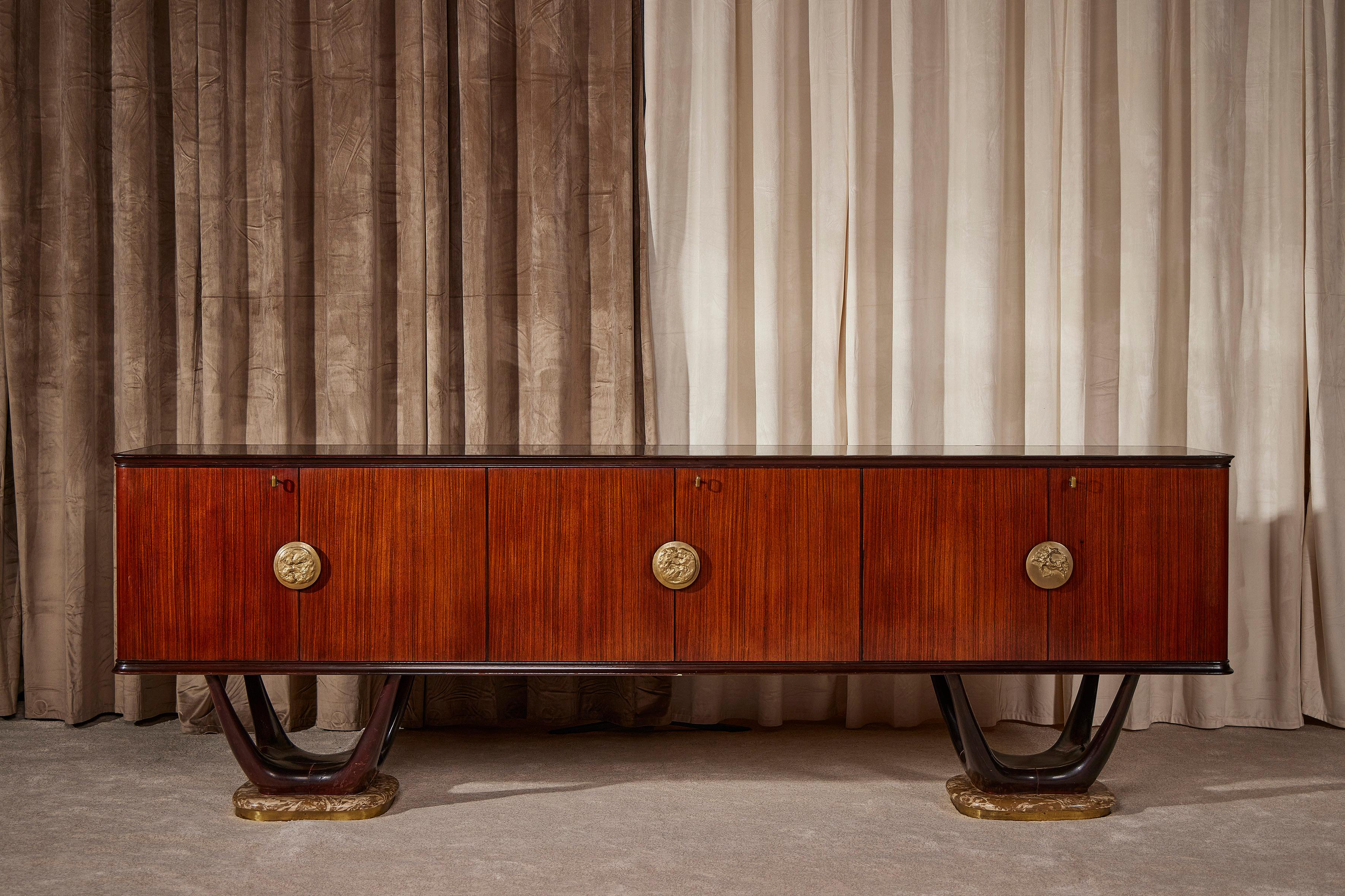 Splendido sideboard di altissima qualità artigianale italiana disegnato da Fratelli Turri e prodotto negli anni cinquanta da Dassi. Questa credenza poggia su due basi scultoree di noce tinto in un elegante marrone scuro e piedi in onice con bordo in