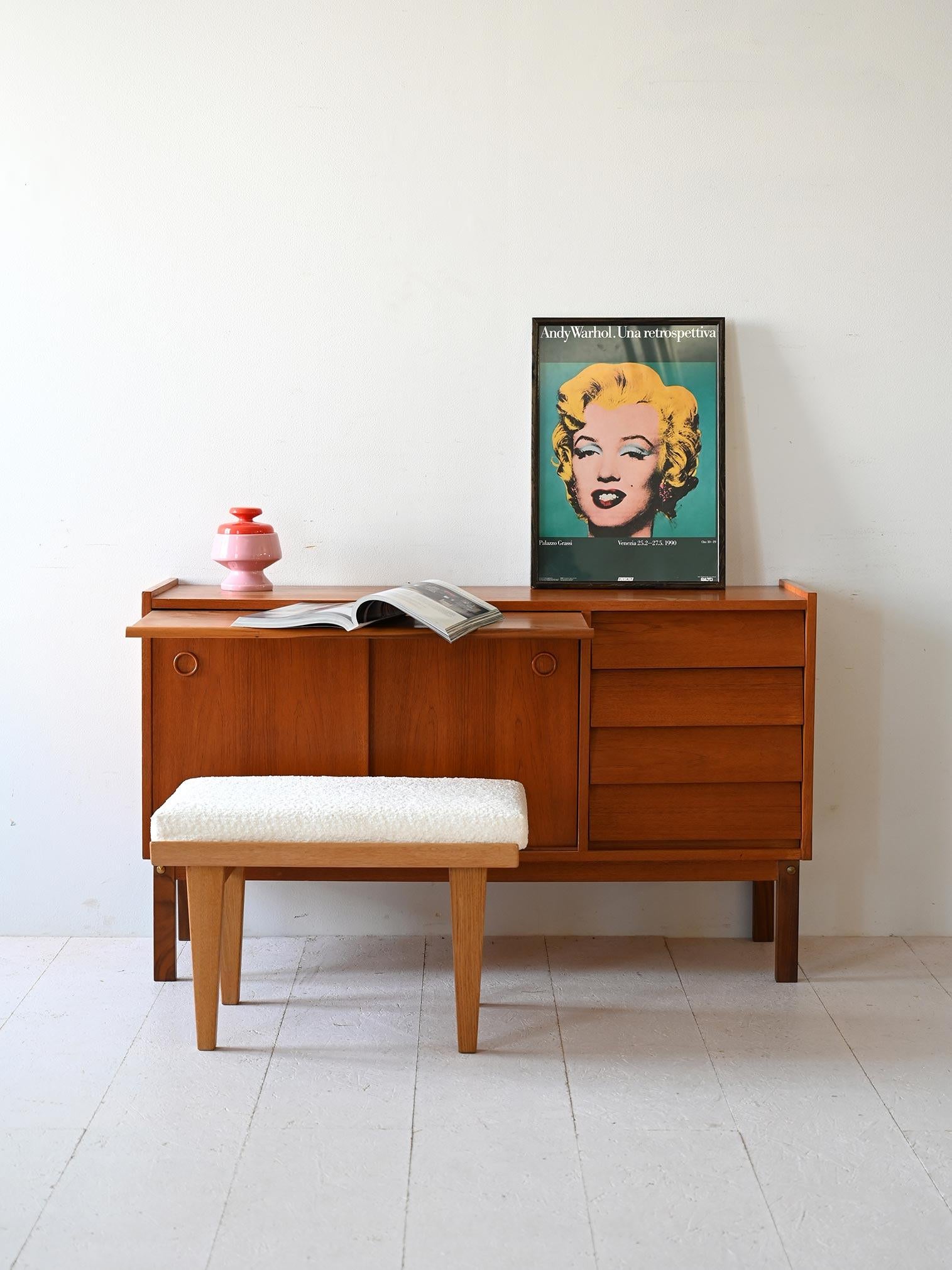 1960s teak storage cabinet with drawers and sliding doors. The pull-out top allows it to be transformed into a small desk. 

The modern lines and functional design make this sideboard suitable for inclusion in various rooms in the home.  
Good
