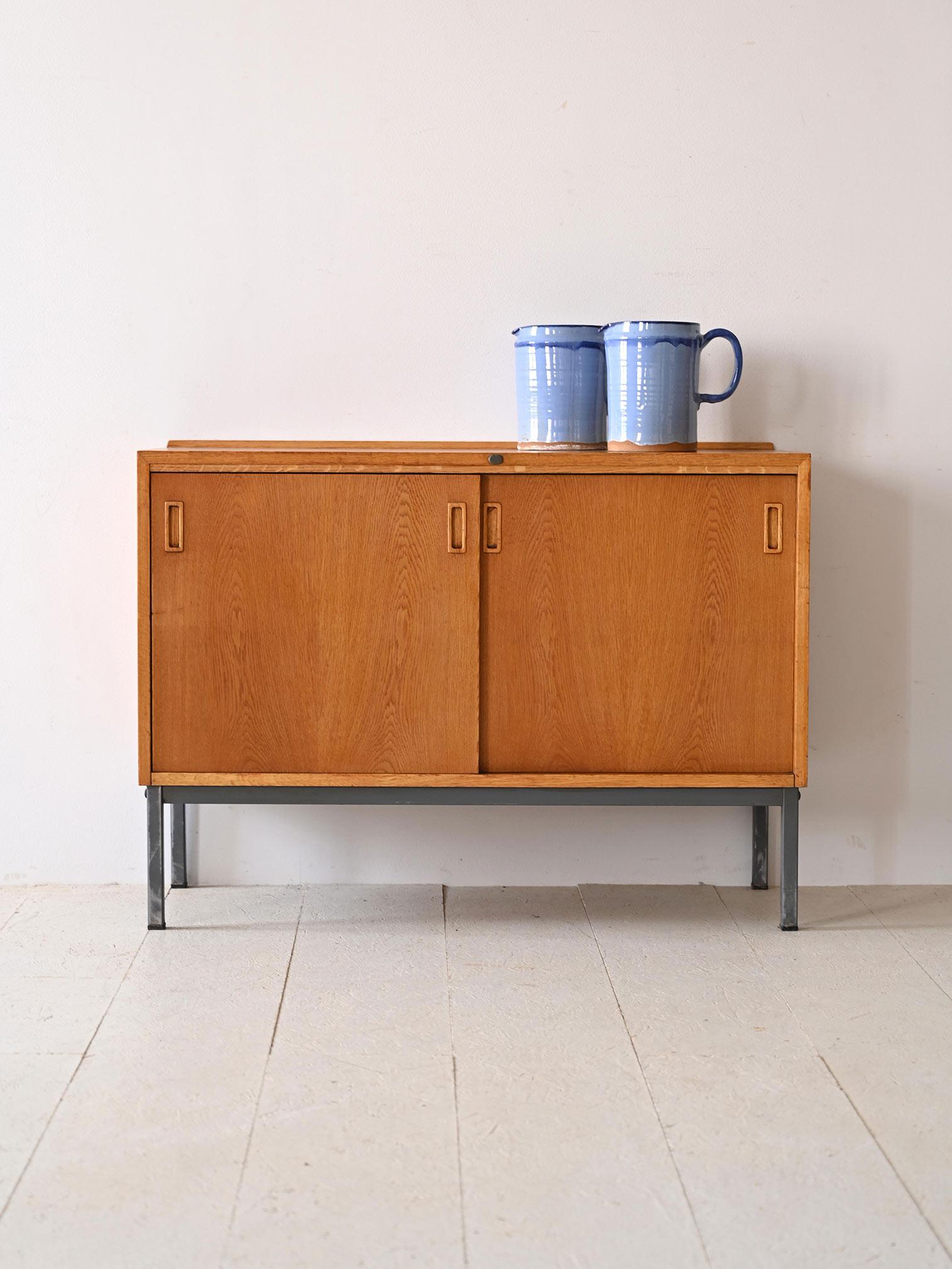 Original vintage sideboard of Scandinavian origin.                                                          Made of fine oak, it is distinguished by its square shape that enhances the minimalist elegance typical of the period. The two sliding doors,