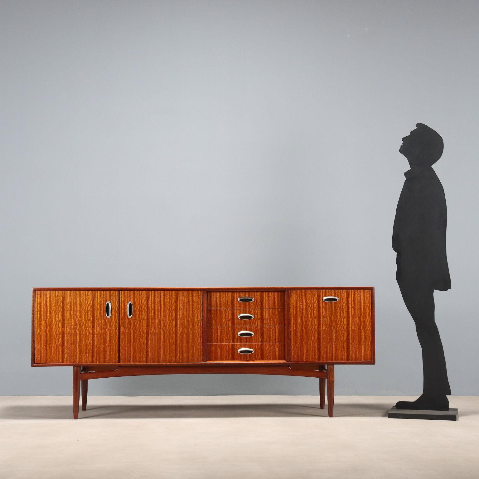 Sideboard vintage impiallacciato in legno di teak con anta a ribalta, quattro cassetti e ante a battente; maniglie con inserti in metallo. Arredo che ha beneficiato di un restauro completo nei nostri laboratori.