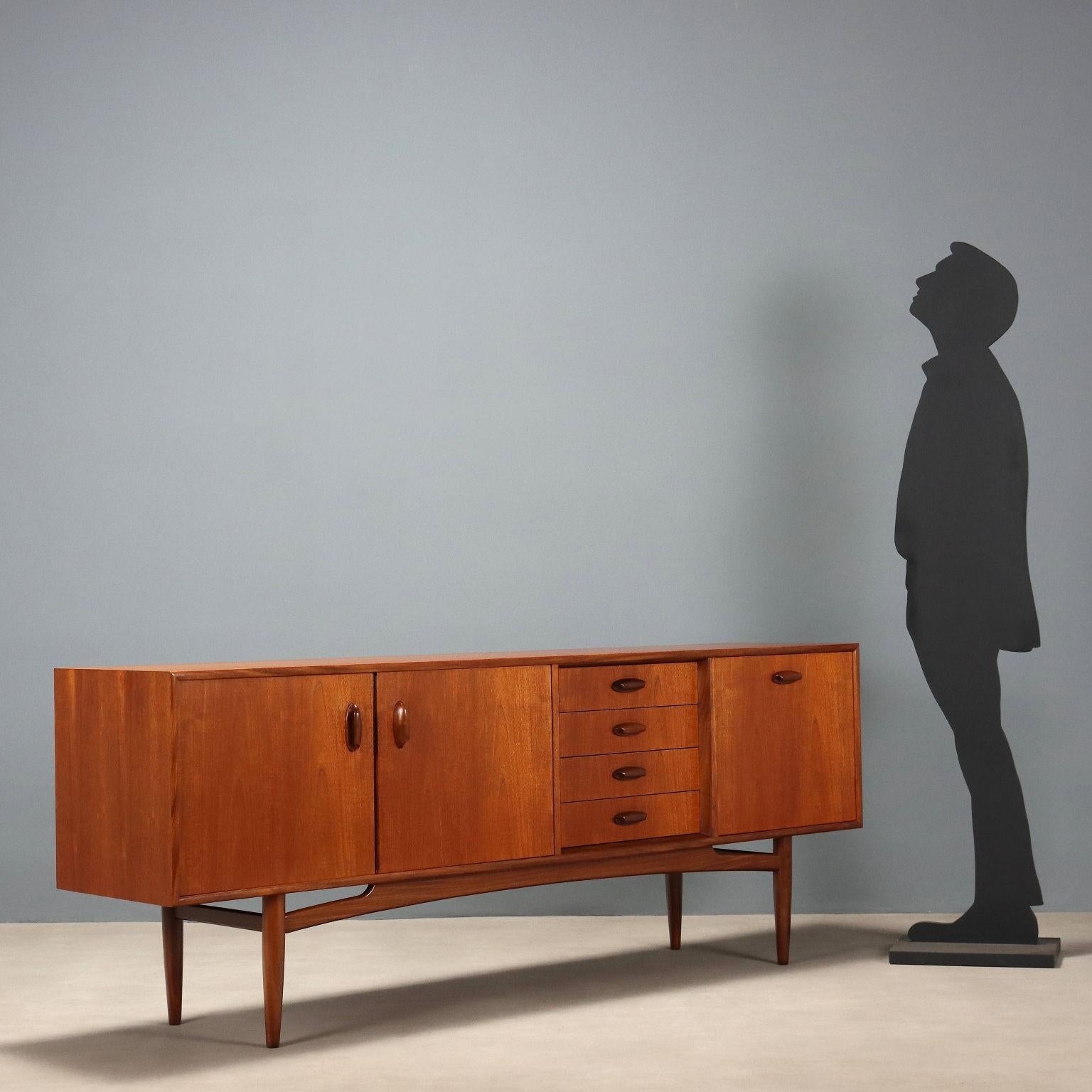Credenza vintage impiallacciata in legno di teak con maniglie, in tonalità più scura, presenta Cassetti, anta a ribalta e doppie ante battenti. Mobil che ha beneficiato di un restauro completo nei nostri laboratori.