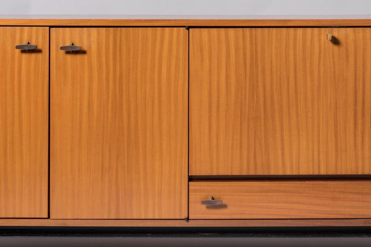 Sideboard - Marcel Gascoin zugeschrieben - um 1960
Massives Teakholz, Mahagoni-Furnier und schwarz lackiertes Metall
Drei Türen, eine Bar und eine Schublade, auf einem quadratischen, schwarz lackierten Metallrohrsockel.
Maße: H88 x B224 x T46