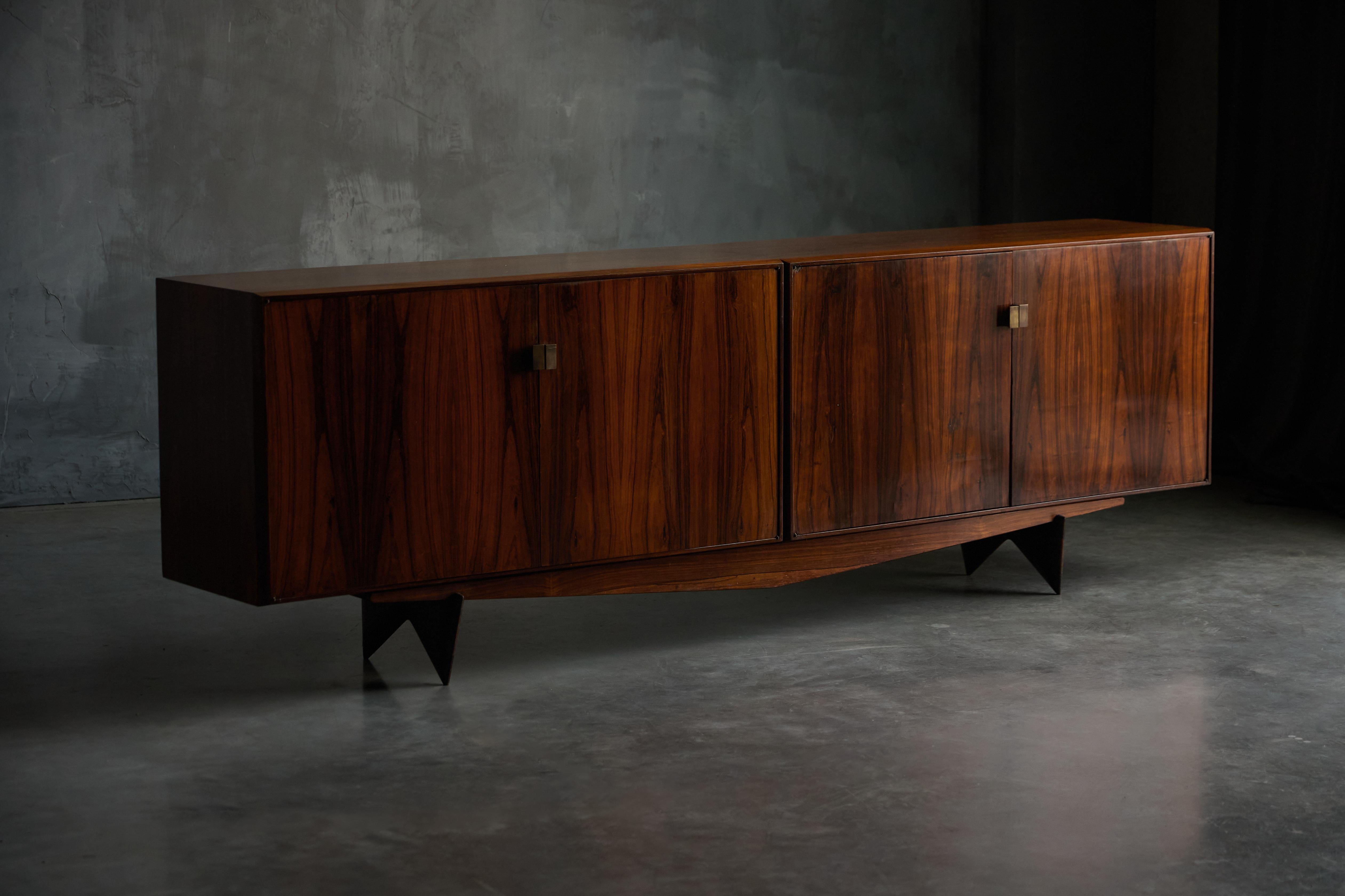 Questa credenza, disegnata da Carlo Hauner per Forma Móveis e Objetos de Arte, rappresenta un notevole pezzo di arredamento moderno brasiliano di metà secolo. Realizzato principalmente in ricco legno massiccio di Nogueira e completato da