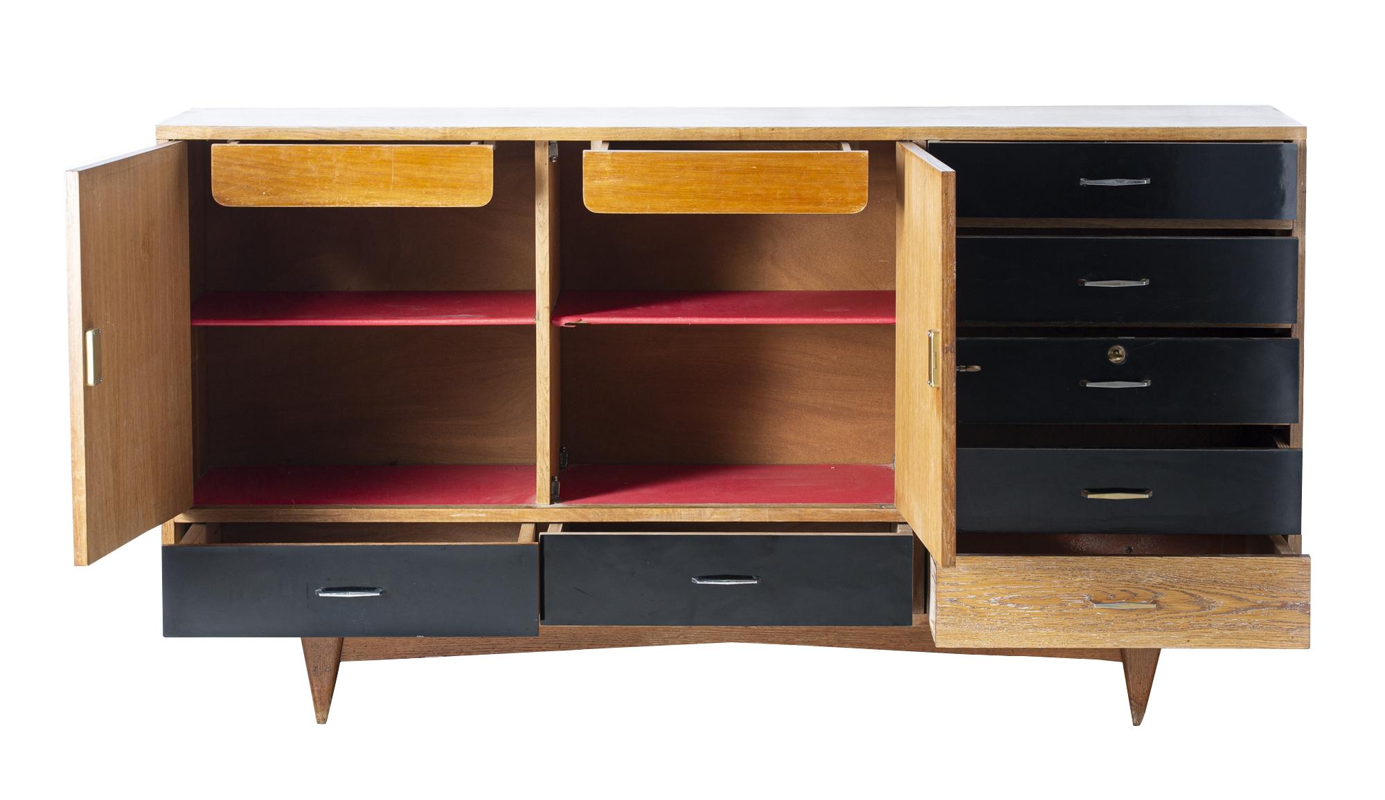Sideboard from the 1950s designed by Charles Ramos (born in 1925) and edited by Magnani.

Ash structure resting on four saber legs, with two hinged doors, two drawers under the doors and five drawers in a row, in an alternation of ash and black
