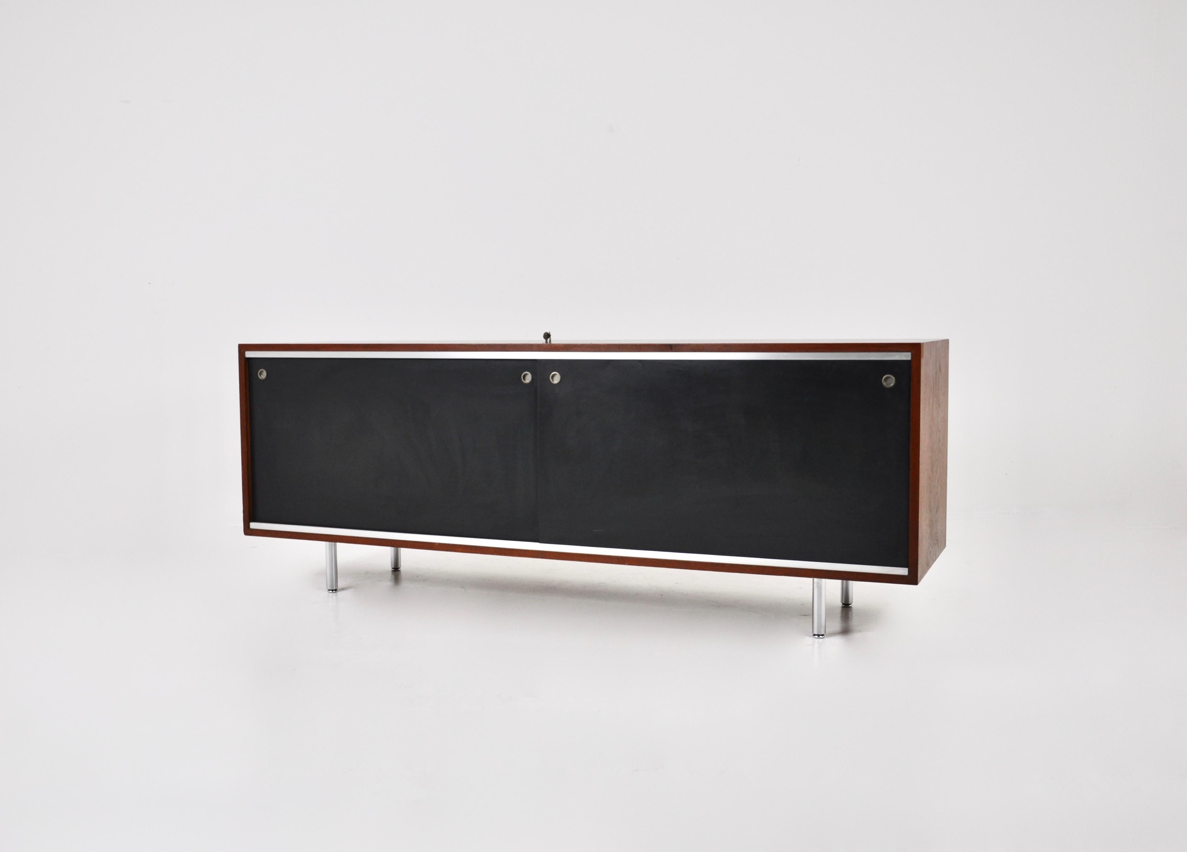 Wooden sideboard with 2 sliding doors each containing 2 height-adjustable shelves. Metal feet. The keys are stamped Herman Miller. Wear and tear due to time and age. 