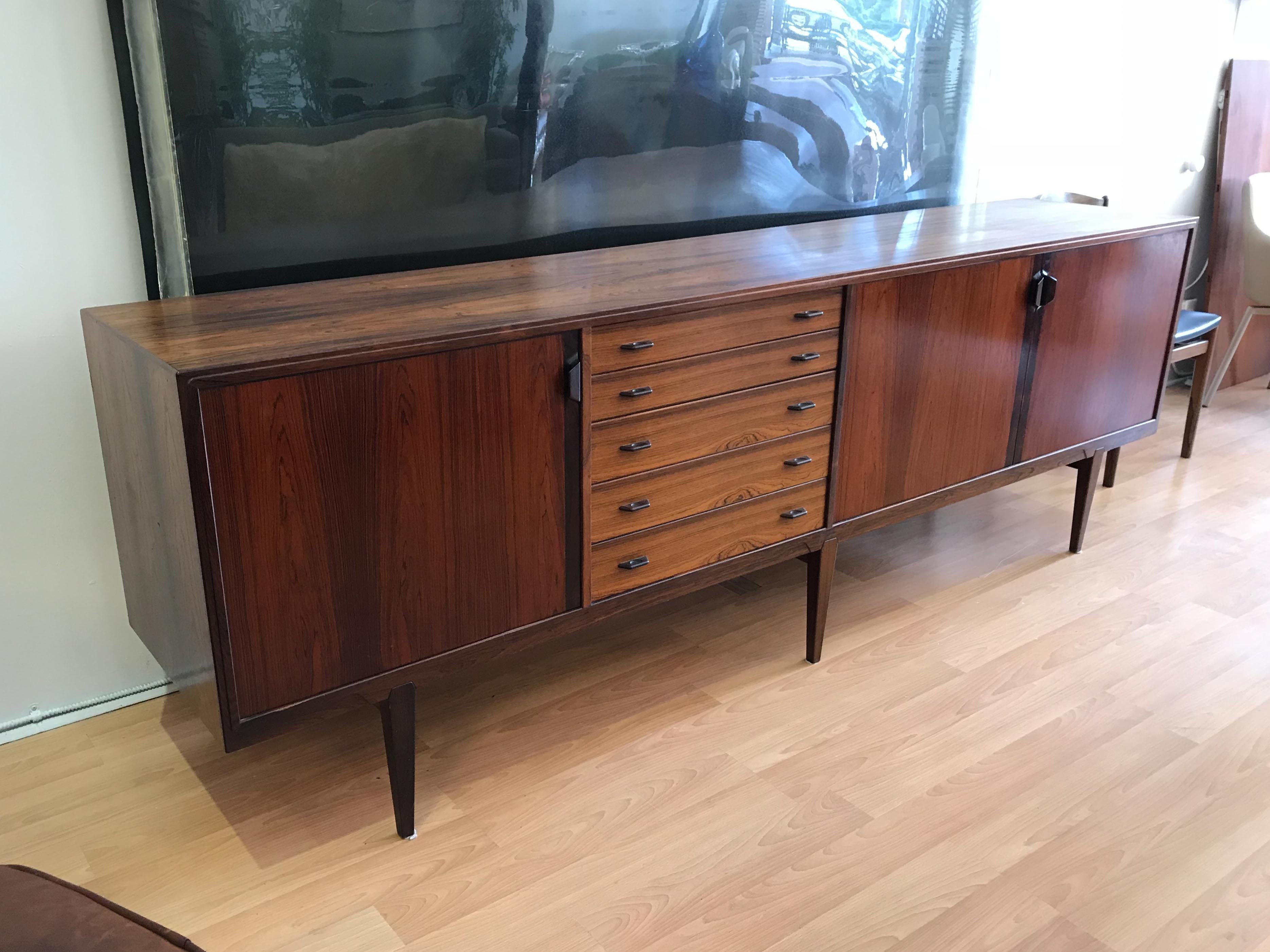 Designed by Henry Rosengren Hansen for Brande Møbelindustri this large sideboard offers plentiful storage, with five drawers and adjustable shelving behind three doors with brass hardware and carved handles.

In very good vintage condition, please