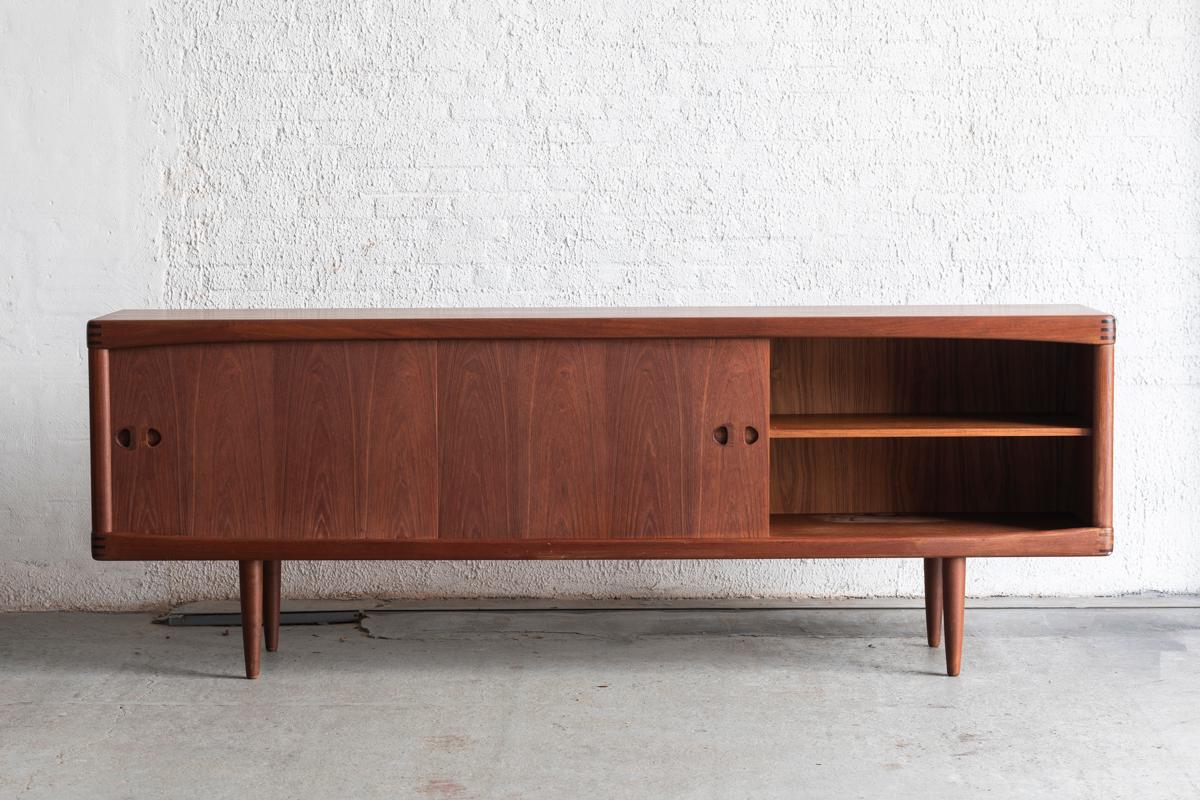 Sideboard entworfen von H.W. Klein und wurde in den 1960er Jahren von Bramin in Dänemark hergestellt. Dieses aus Teakholz gefertigte Möbelstück weist einen hohen Verarbeitungsgrad auf: die geschnitzten Griffe, die massiven Palisanderleisten, die an