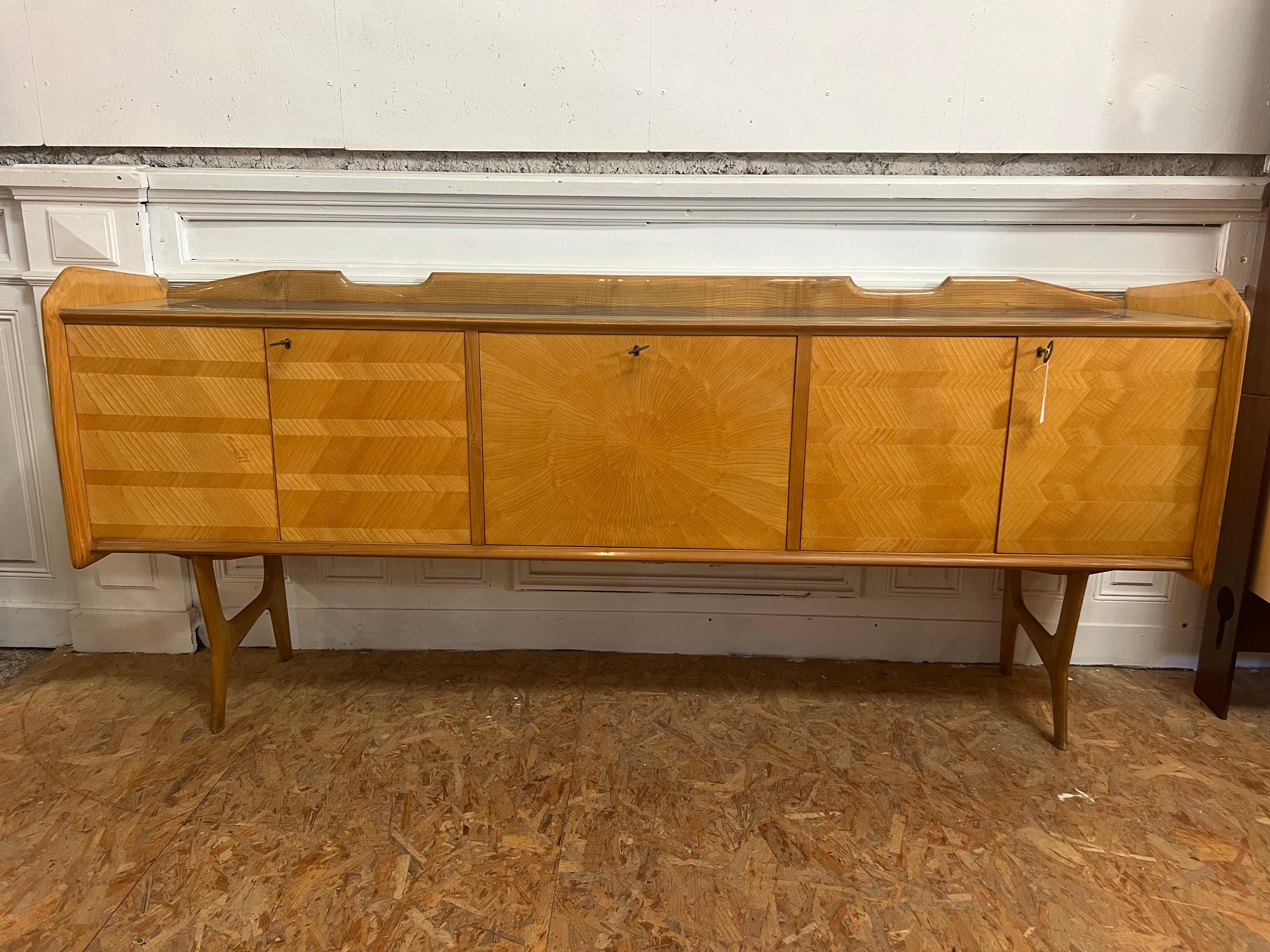 4-door sideboard and central door opening onto an Ico Parisi bar from the 1950s
the splashback is in light wood, honey color with very large marquetry work on the doors, and especially this sun on the central door
the top is in bluish and white