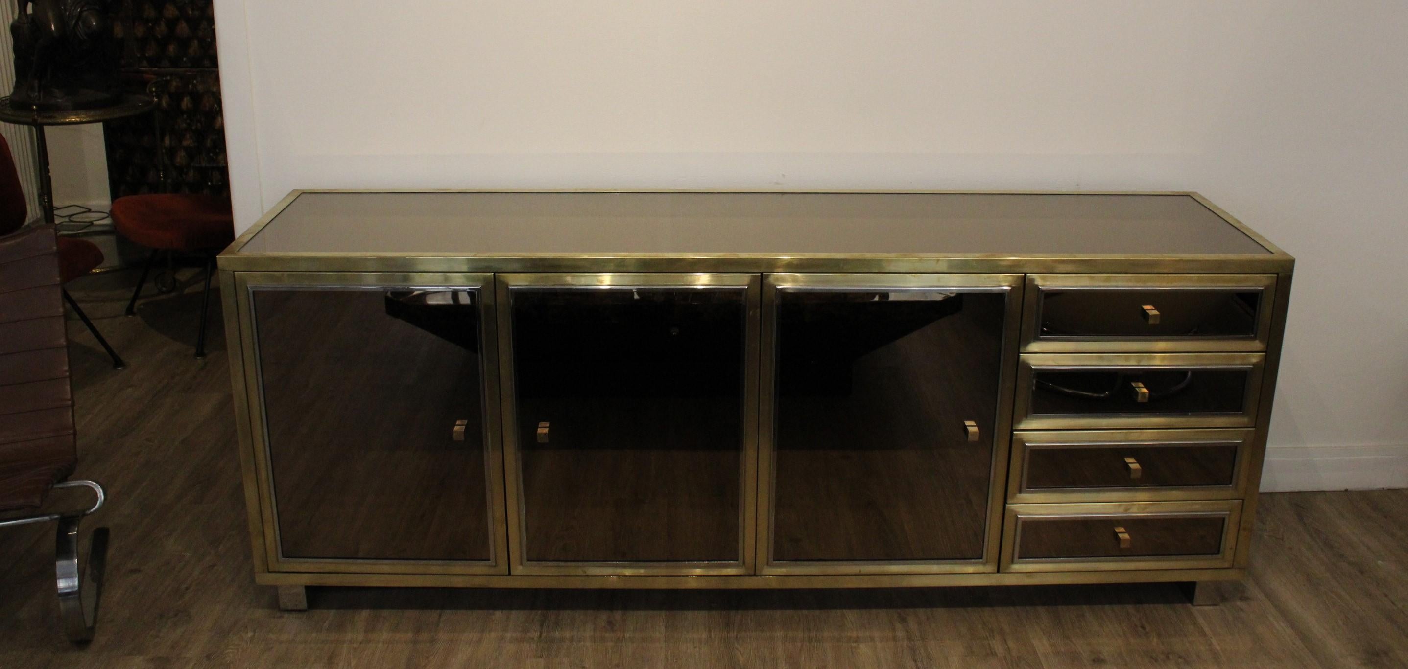Sideboard in brass and mirror designed by Michel Pigneres. 
With a mirror tray, 3 cabinet doors and 4 drawers (each with mirror inserts)
20th century.

In very good condition, wear consistent with age and use.

Height : 76.5cm 
Width : 200