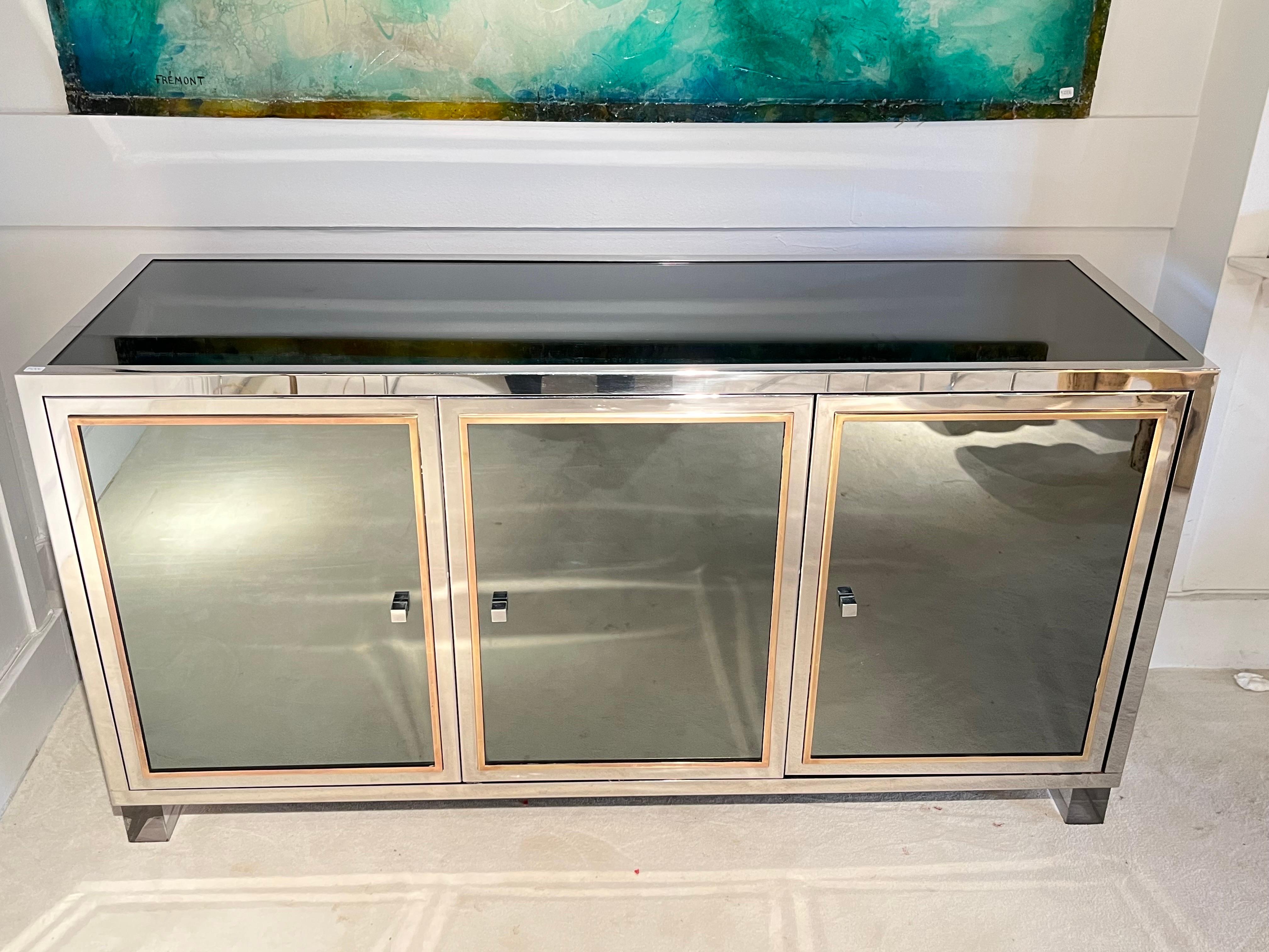 Rare 3 doors mirrored Sideboard with chrome and brass details by Michel Pigneres
2 lucite feets
black formica interior with 1 shelf
good vintage condition

   