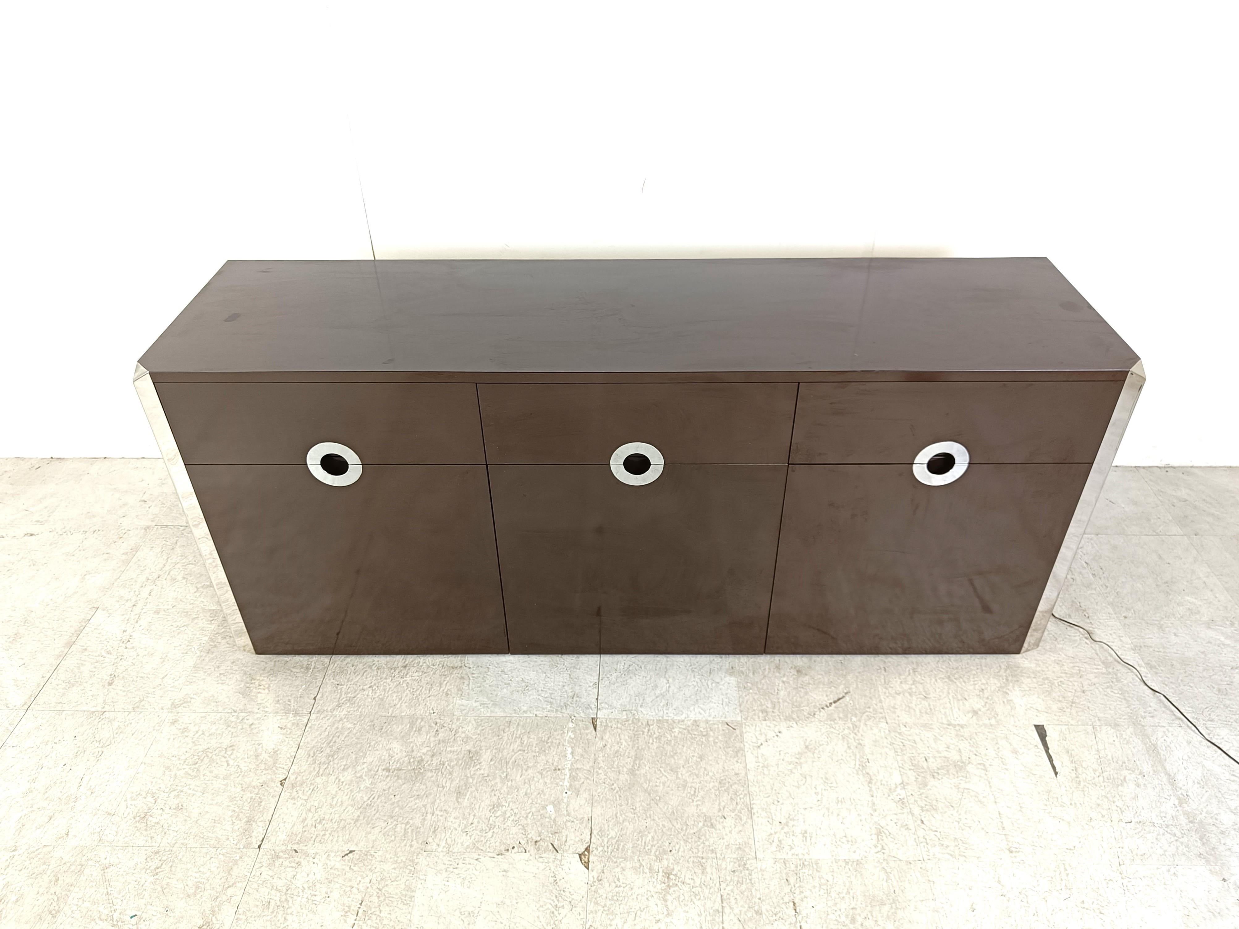 Brown lacquer sideboard with chrome handles and edges designed by Willy Rizzo for Cidue.

The sideboard has an illuminated bar compartment with a fold down door.

Good condition

1970s - Italy

Dimensions:
Lenght: 177cm/69.68