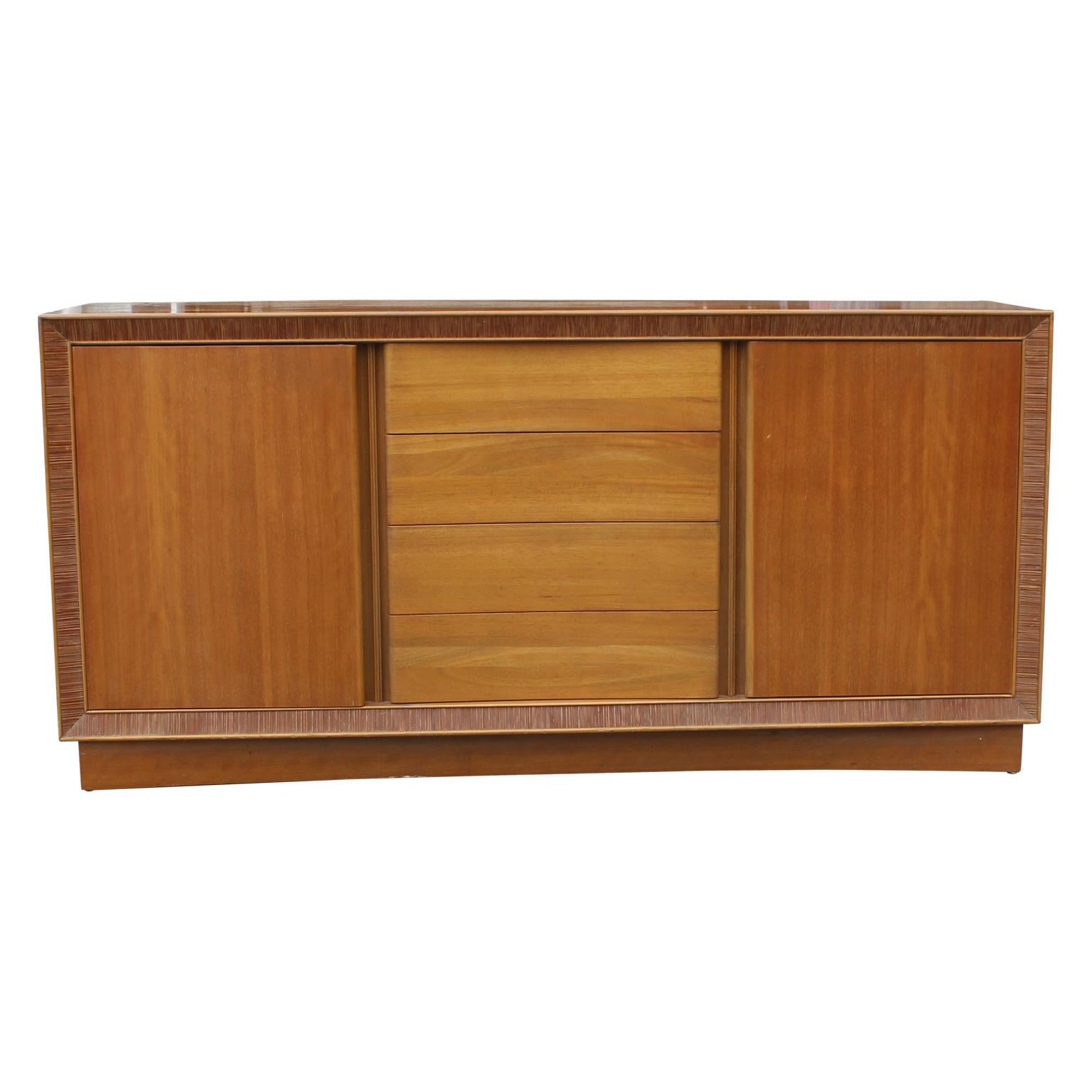 Beautiful sideboard by Paul Frankl for Brown & Saltman. It has a ribbed wood detailed boarder. The middle section has three drawers and the sides have doors in front of shelving. In great vintage condition.