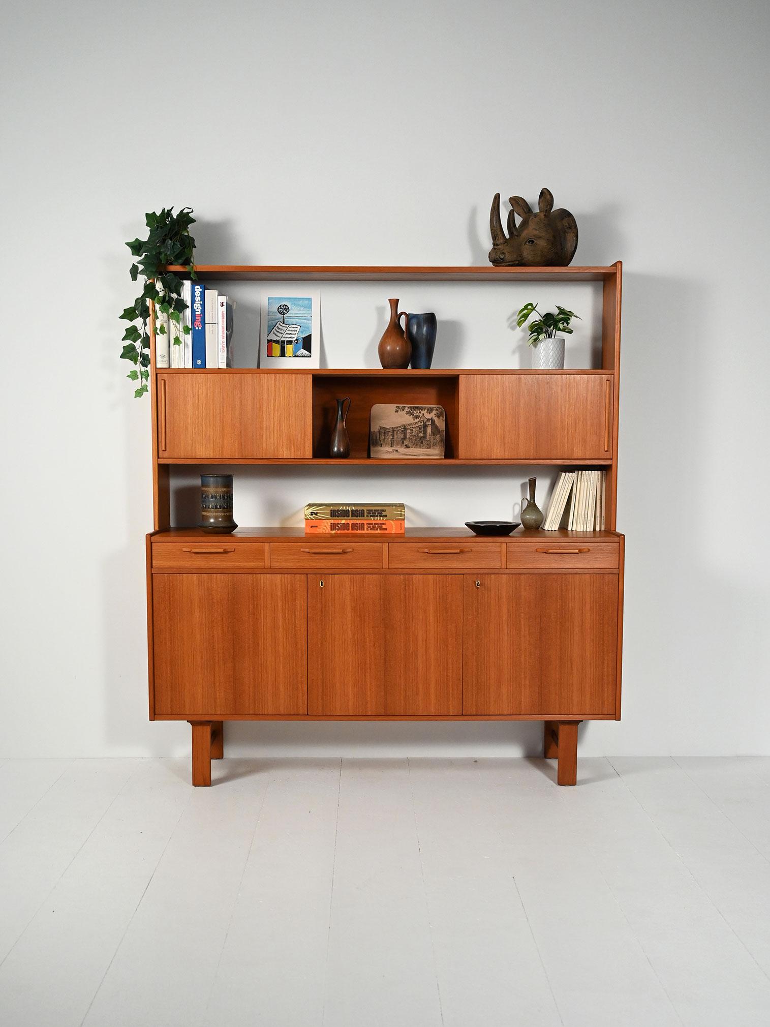 Sideboard scandinavo in teak con alzata: vani a scorrimento superiori, quattro cassetti scolpiti e tre ante inferiori con ripiani interni. Linee razionaliste.

Sideboard scandinavo anni ’60 in teak con alzata integrata. La parte superiore offre due