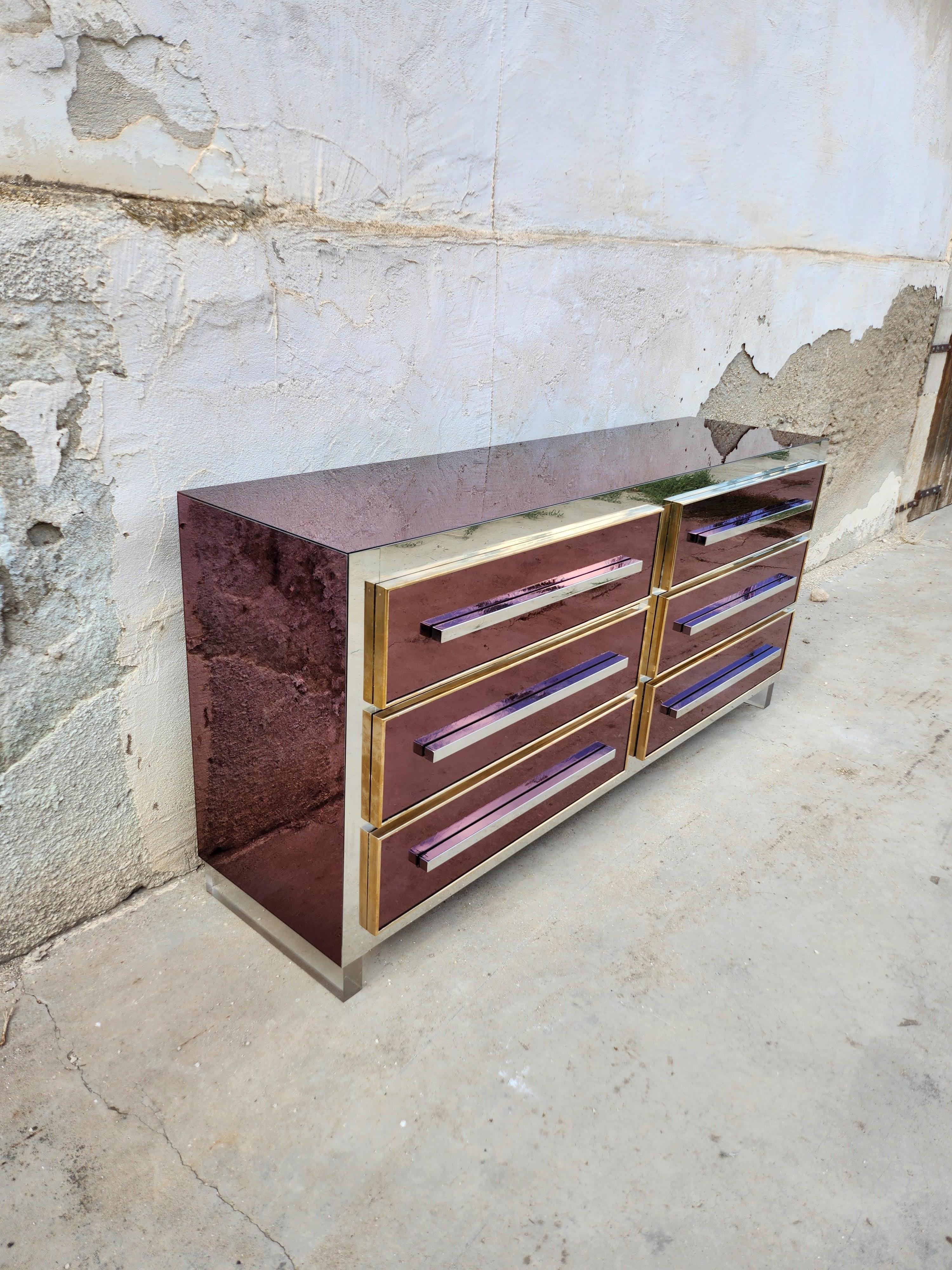 Important chest of drawers fully lined  externally in mirror of a rare purple color, consisting of six drawers , chrome-plated brass handles, drawer frames in  polished brass , plexiglass feet, 
Interior of drawers fully lined with formica, a few