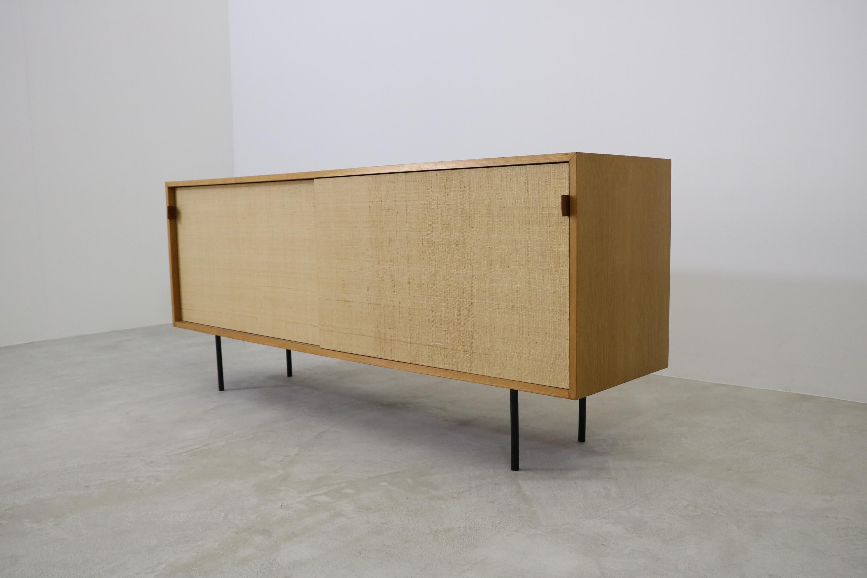 Sideboard credenza (Mod. 123) by Florence Knoll with sliding doors sea grass.
Produced by Knoll International, 1960s.
Frame steel lacquered black, body wood ash, sliding doors sea grass with leather handles.
The sideboard comes from first