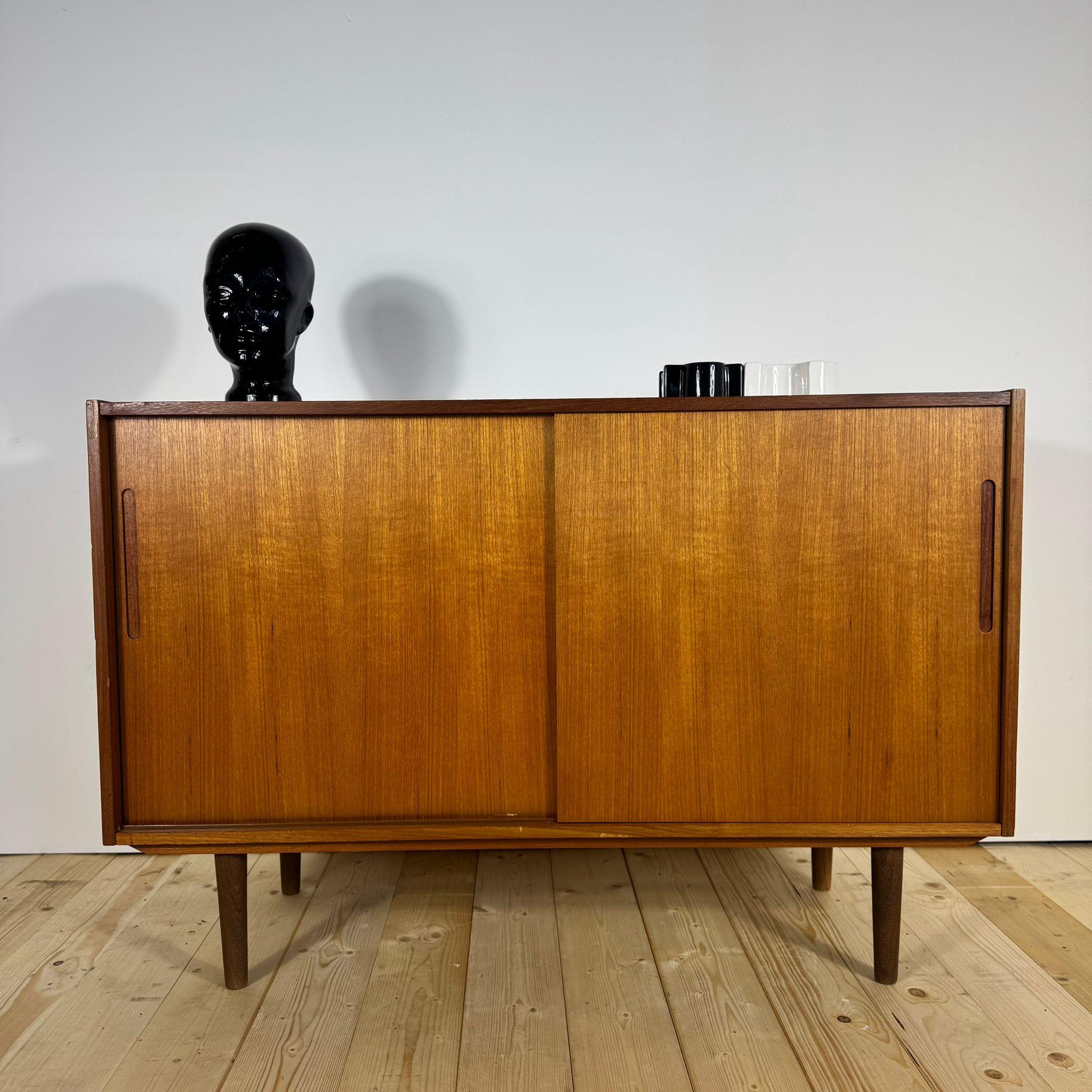 Questa elegante sideboard in teak impiallacciato, realizzata in Danimarca negli anni Sessanta, incarna perfettamente l’essenza del design Mid-Century scandinavo: linee sobrie, proporzioni armoniose e un’eccellente qualità artigianale. Il fronte con