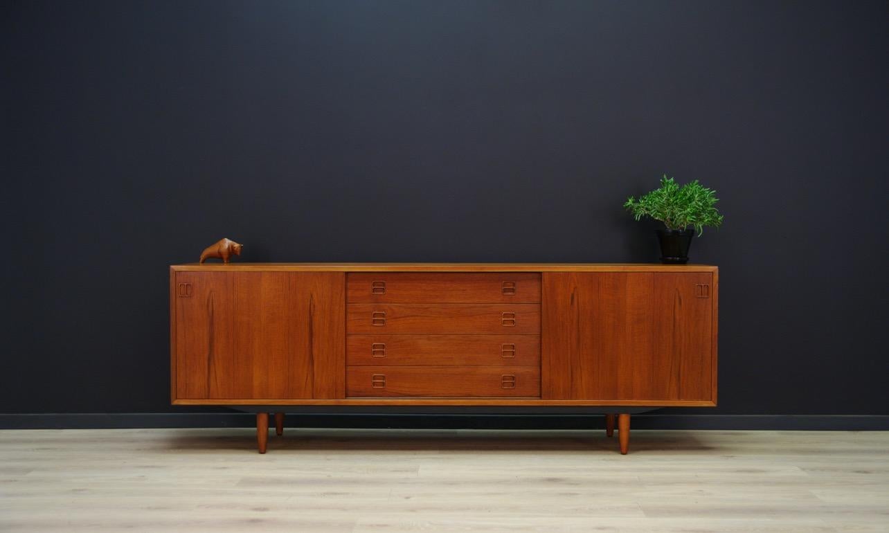 Fantastic sideboard from the 1960s-1970s, Danish design. Minimalist form finished with teak veneer. Spacious interior with a shelf behind the sliding doors. Four drawers in the middle section. Preserved in good condition (small bruises and