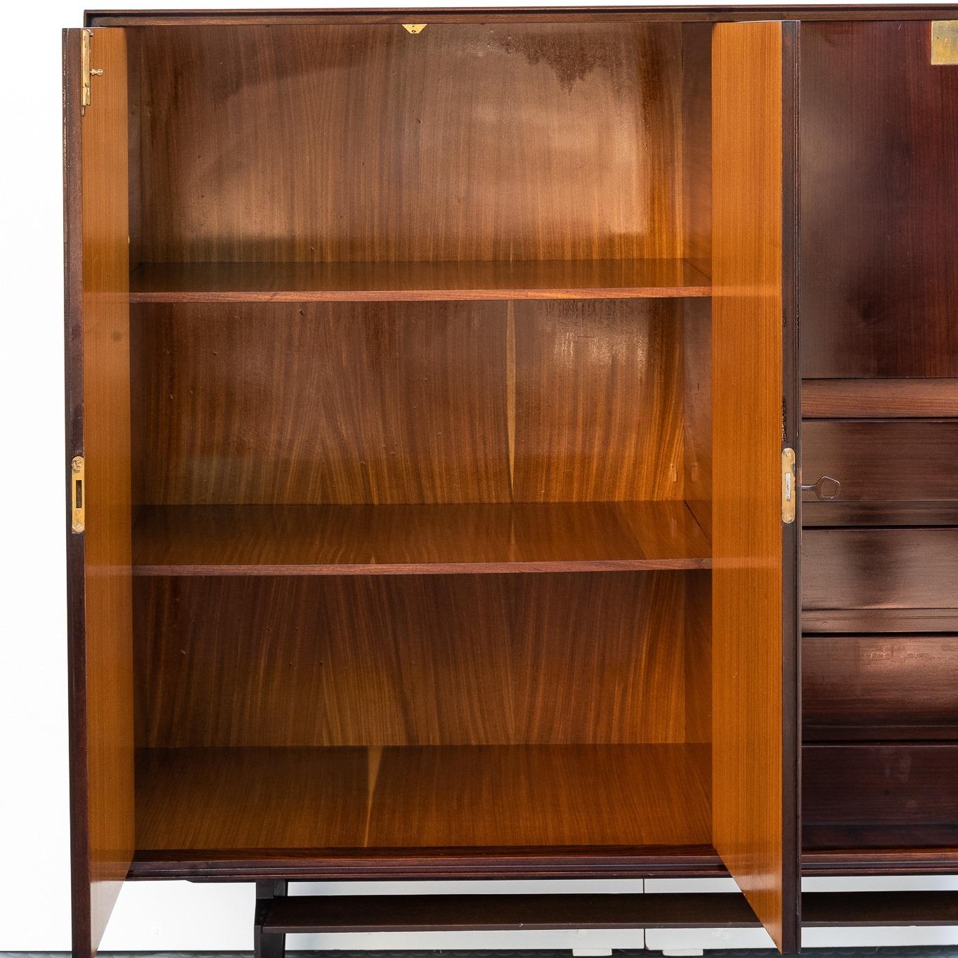 Questa Sideboard dell'anno 1960 ha due sportelli a battente con cassetti realizzati in legno impiallacciato in palissandro,  con maniglie in ottone. Il Designer è Edmondo Palutari, Produzione di Vittorio Dassi dal 1960-1969.  
L'anta a ribalta sul