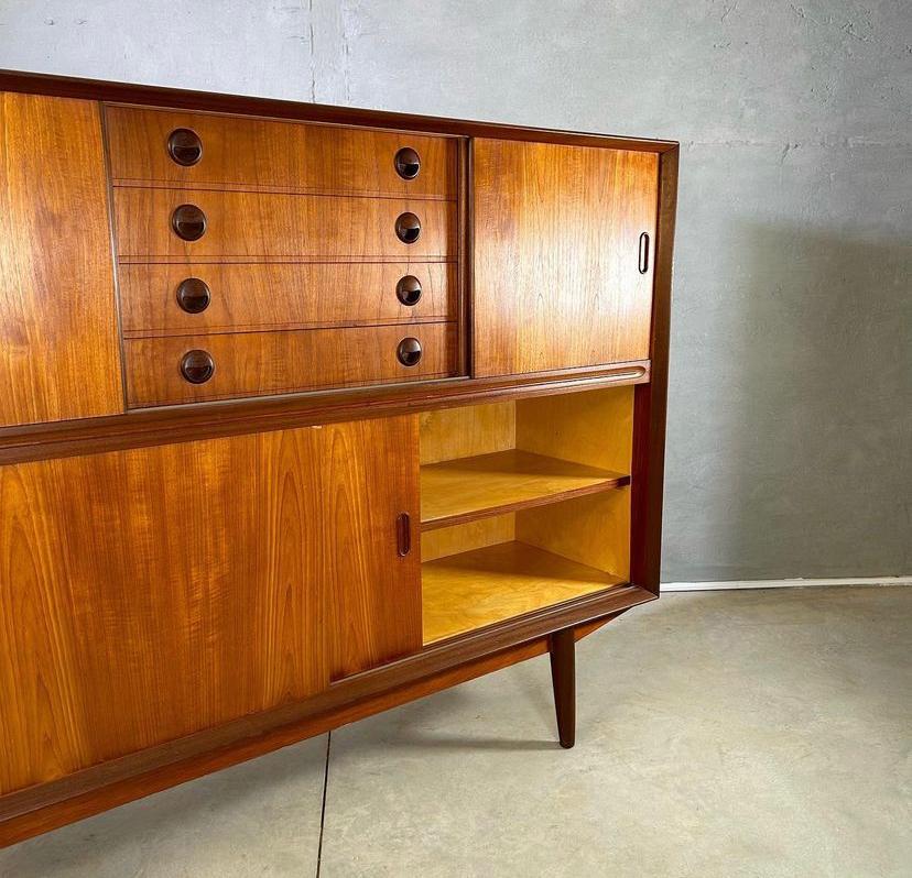Stunning Mid-Century Modern danish high sideboard for Genega Møbler in teak wood, 1960s Denmark.

This sideboard has a well made solid teak base, Subtle design features and typical mid-century Danish design looks. Carved grips on the four sliding