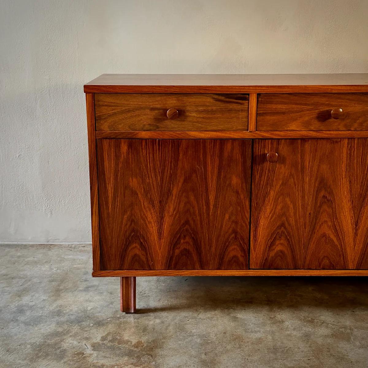 Italian 1970s console, credenza, or sideboard in rich walnut wood, featuring four rectangular drawers and two large cupboards below. This piece exemplifies mid-century Italian design with its clean lines and elegant functionalism, providing
