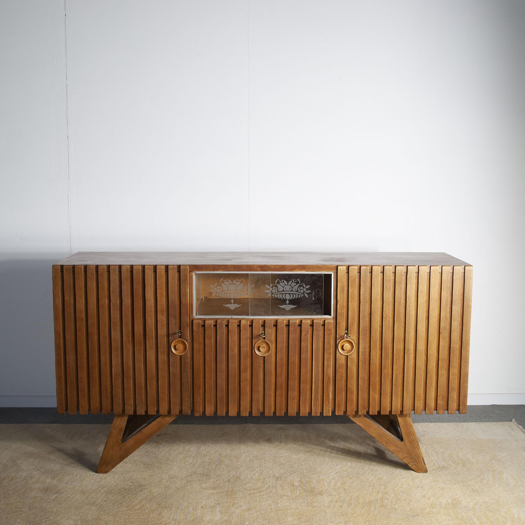 Early 1950s Italian sideboard, light oak wood frame composed of two side doors with related drawers a small central display case and a bar compartment . The tapered oak type and the slender, assertive style lead the object study to the Turin school