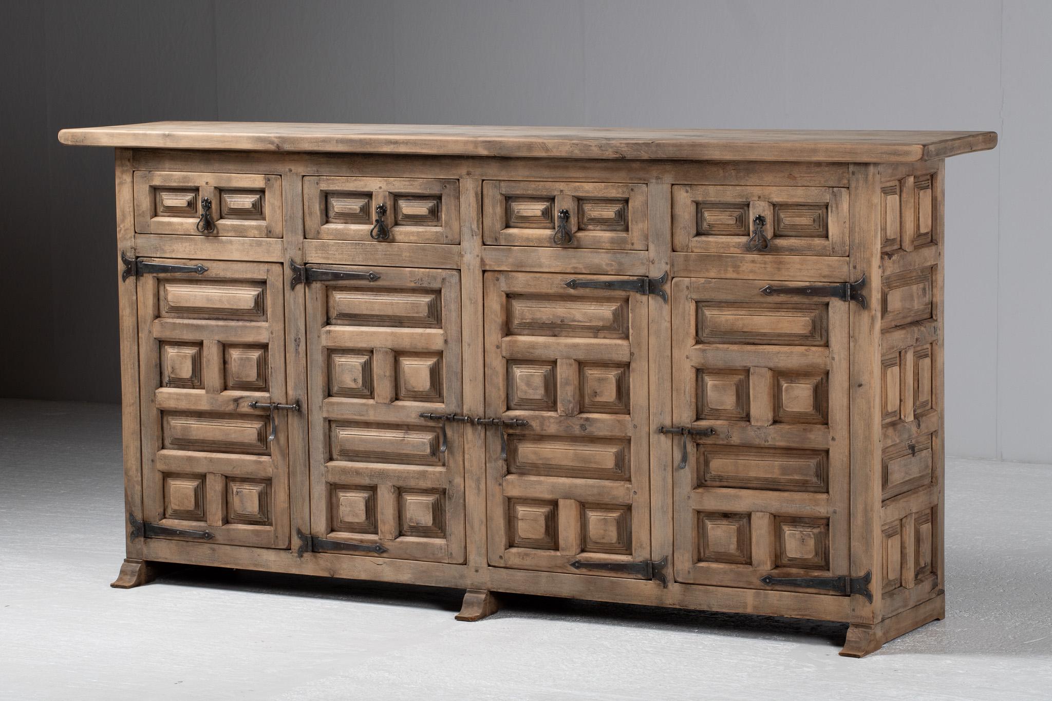 Stolid yet richly patterned, this monumental sideboard captivates with its rhythmic interplay of shadow and relief. The facade unfolds as a procession of deeply carved geometric panels, their square motifs alternating between projection and recess,