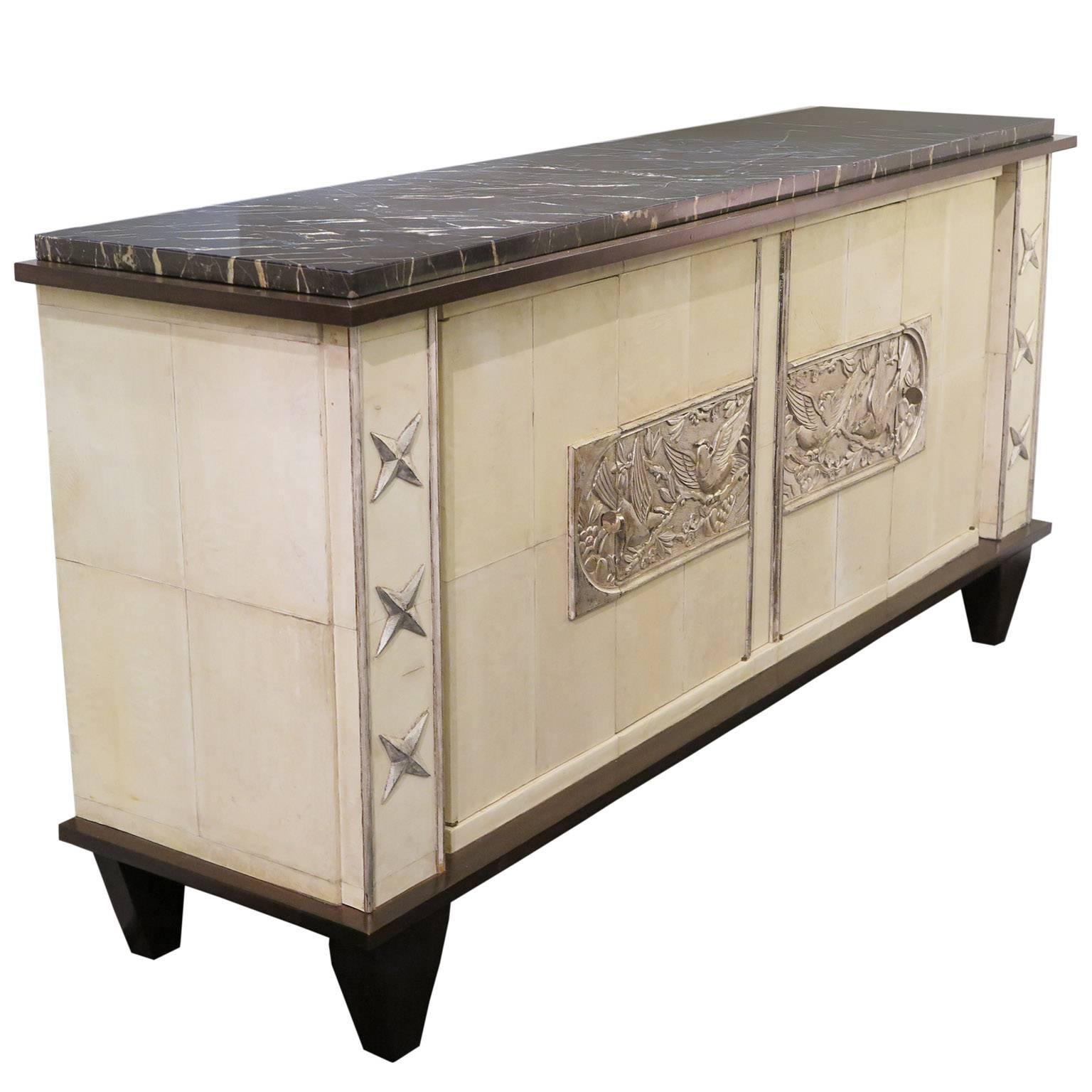 Decorative sideboard with parchment frame and dark mahogany borders and feet. Center relief carving of birds in trees in naturally antiqued silver leaf. Six carved stars in silver leaf decorate the ends of the sideboard. Original marble top. Two