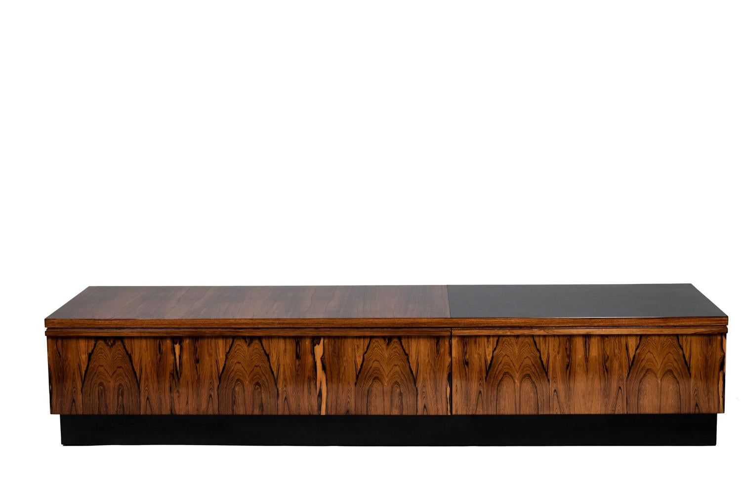 Low sideboard in Rio rosewood. Top partially covered with black laminate. Base of the sideboard in brushed aluminium.

Work realized in the 1970s.