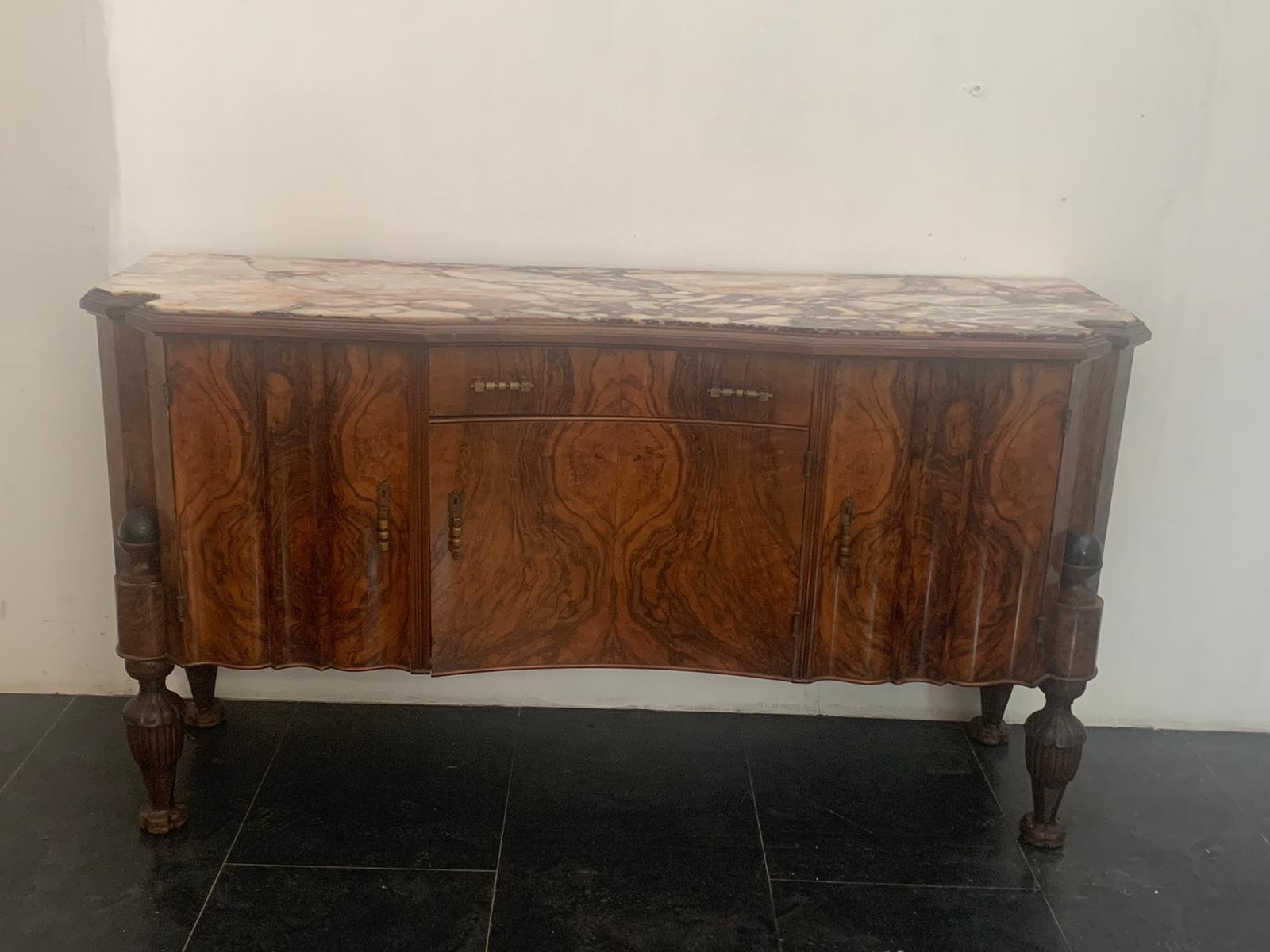 Wavy sideboards with 3 doors and a central drawer. The feet finely carved in elongated pine cone with ebonized sphere above, are inserted in a niche groove. The tops are in marble breccia medicea, exclusive stone and fantastic texture. The wood is