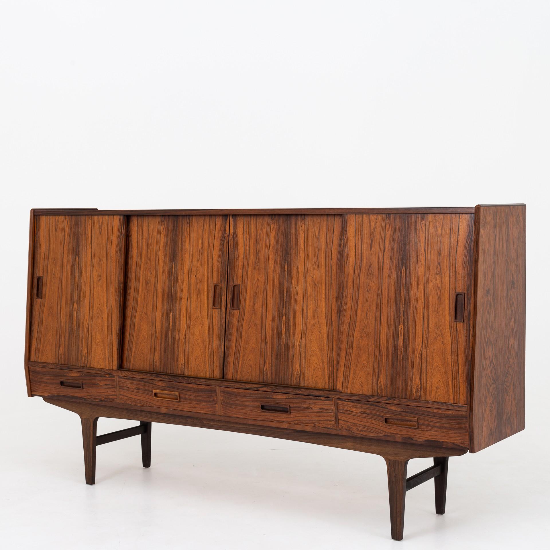 Tall sideboard in rosewood with sliding doors and drawers, mirror in the middle of interior.