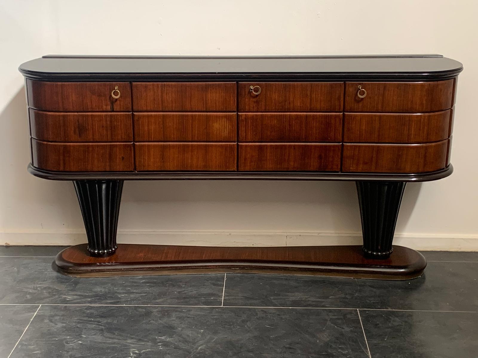 Sideboard attributed to Vittorio Dassi. The elegantly ovalised base narrows towards the profiled centre and is outlined above by ebonizing, below by brass slats. The base accommodates two vase-shaped columns carved in a thousand rows and ebonised,