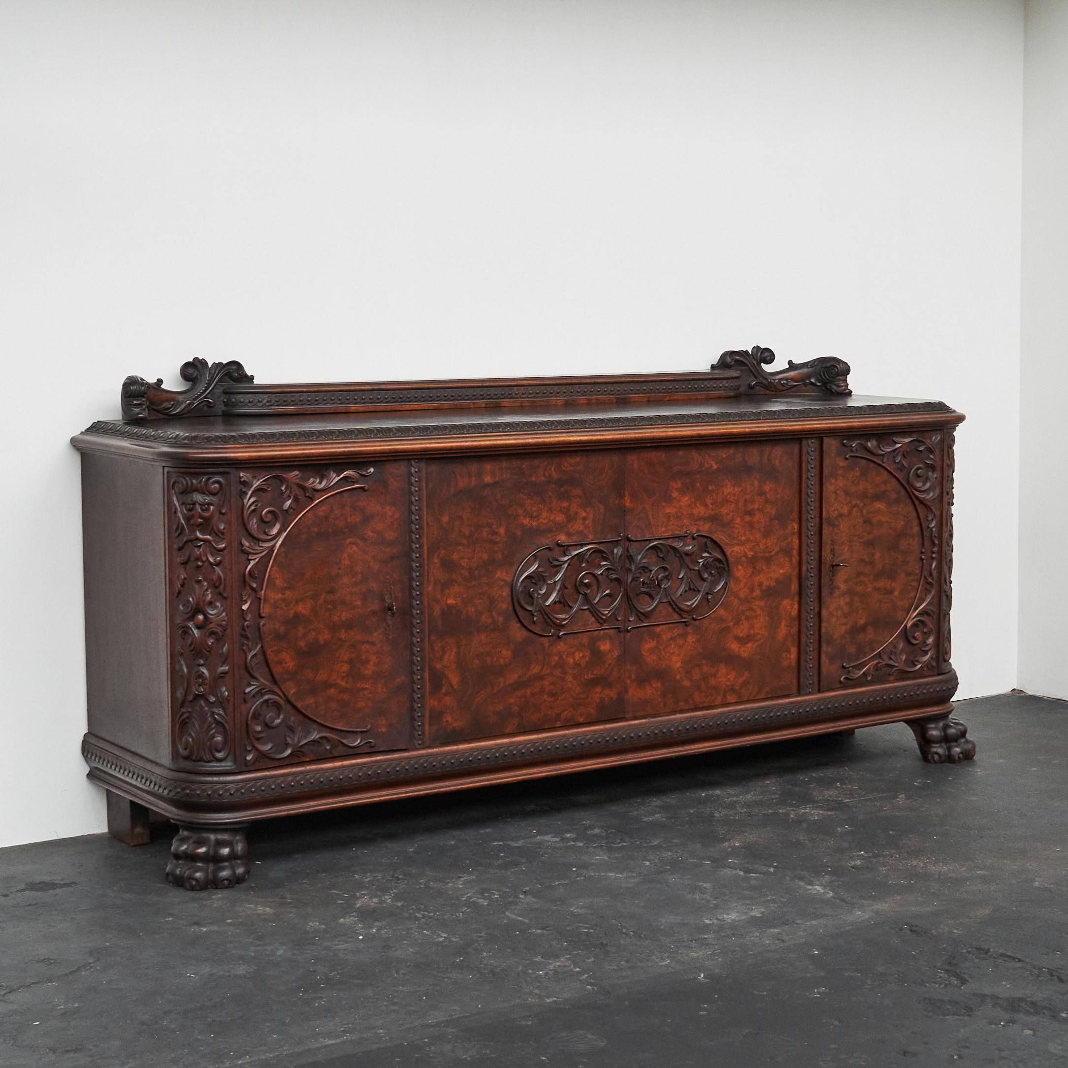 This is a beautiful and unusual sideboard in carved solid wood and walnut burl, made in Europe in the 1940s.

The wonderful and sometimes even grotesque carvings, combined with the wonderful wood grain of the burl make this sideboard a rare and