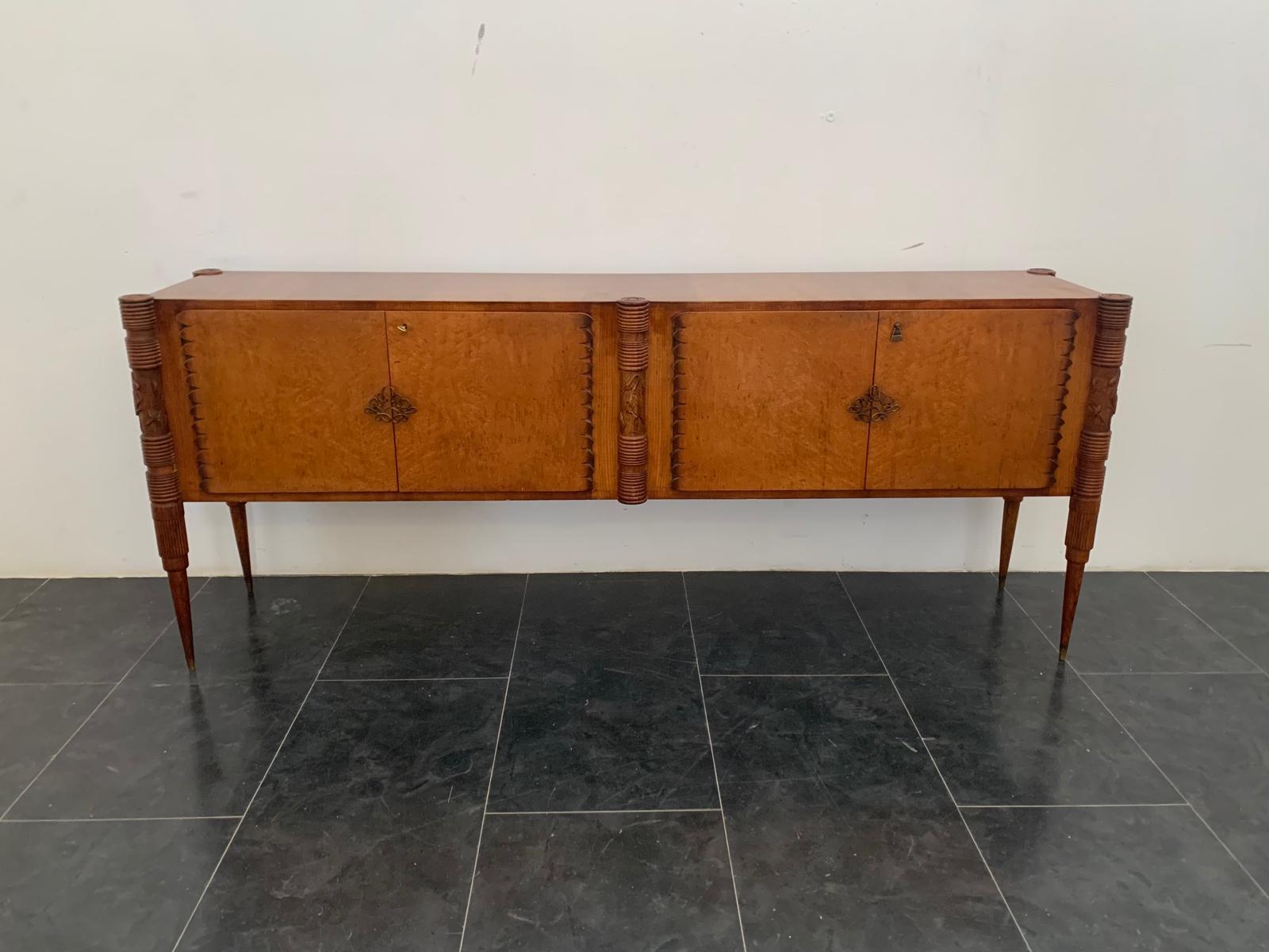 Oak and maple burl sideboard, widely popular in the 1950s.
Unique in its kind, with multiple design details and exclusive finishes that complemented each other, making the piece harmonious and truly one of a kind.
The conical legs are sculpted at