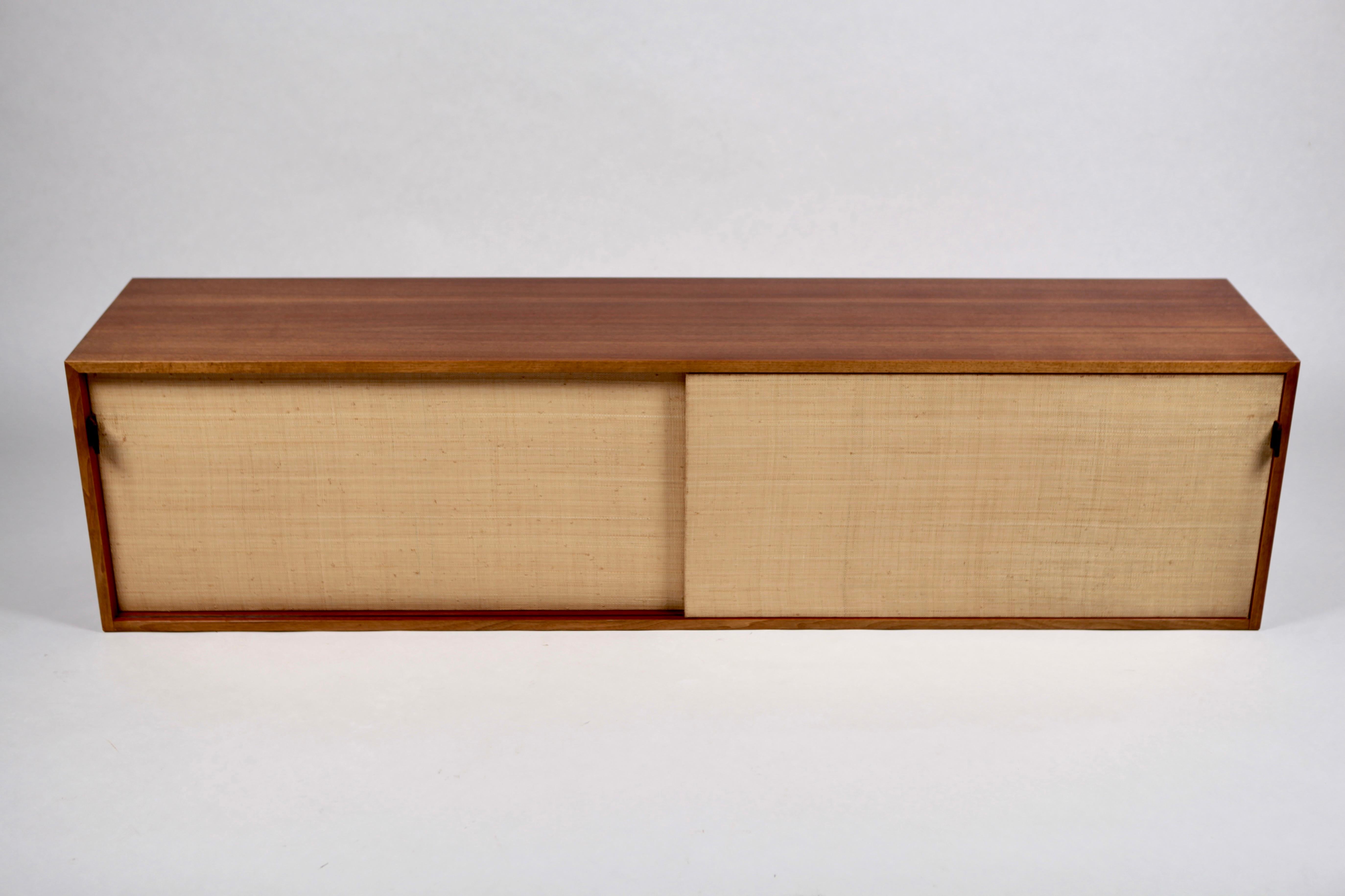 Rare & beautiful floating, wall mounted sideboard by Florence Knoll, designed in 1947, this model in Teak & Raffia, is executed in 1952 in very small edition by Knoll International in Stuttgart. Paper label signed to the back, model 123.
Sliding