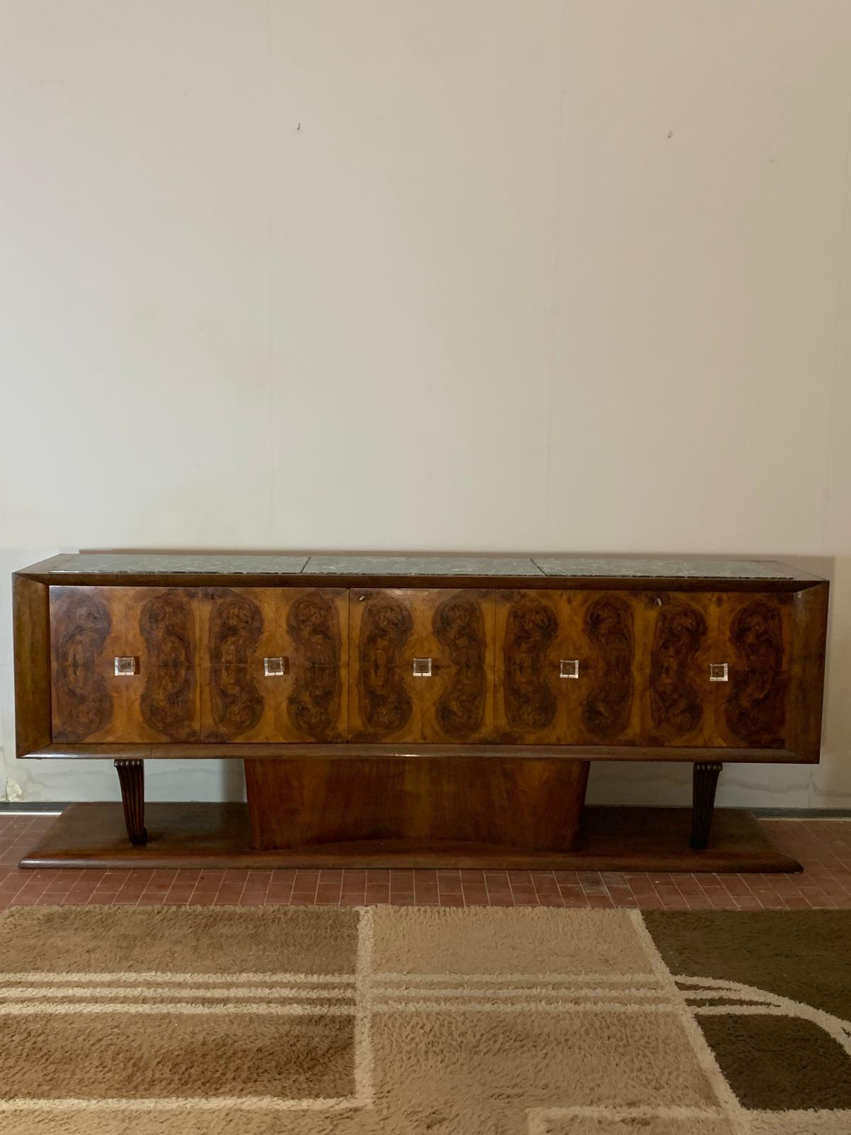 Art Deco Sideboard of Excellent Craftsmanship and Fine Materials
Expertly crafted, this sideboard rests on a solid base supporting a gently curved central body, flanked by two finely carved pilasters. The structure features five doors, made from a
