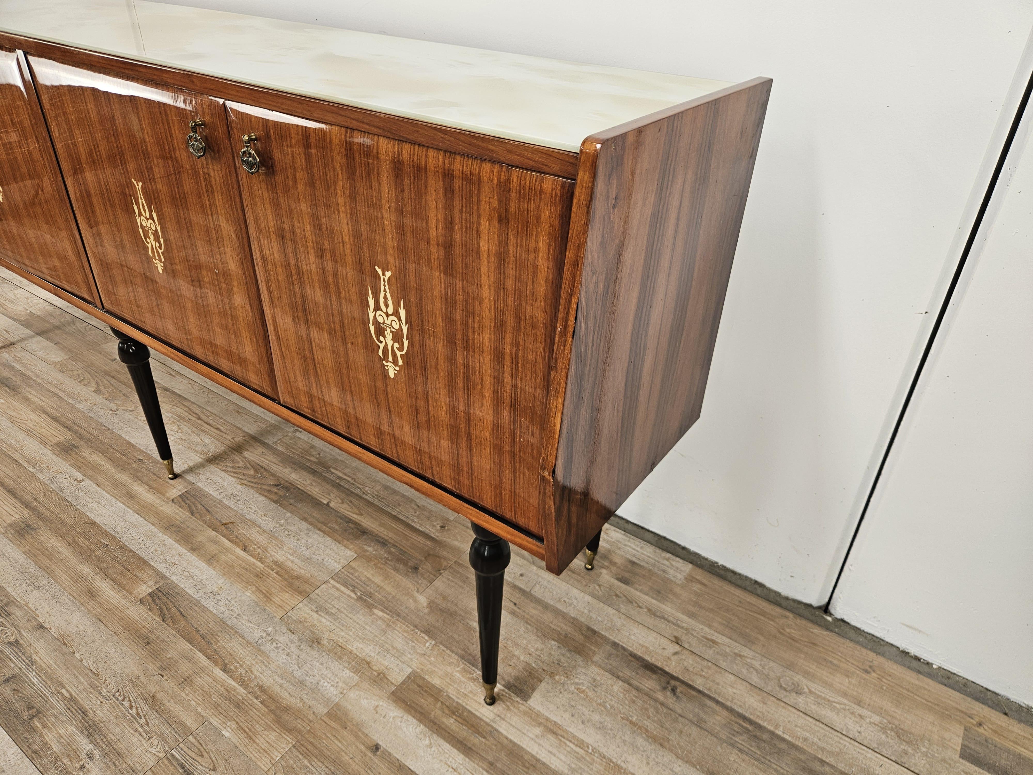 1960s sideboard for dining room or living room, upholstered in mahogany with four doors enclosing two capacious compartments with shelves.

It is finely crafted with an original period glass top and pointed ebonized wood legs.

Shows normal signs of
