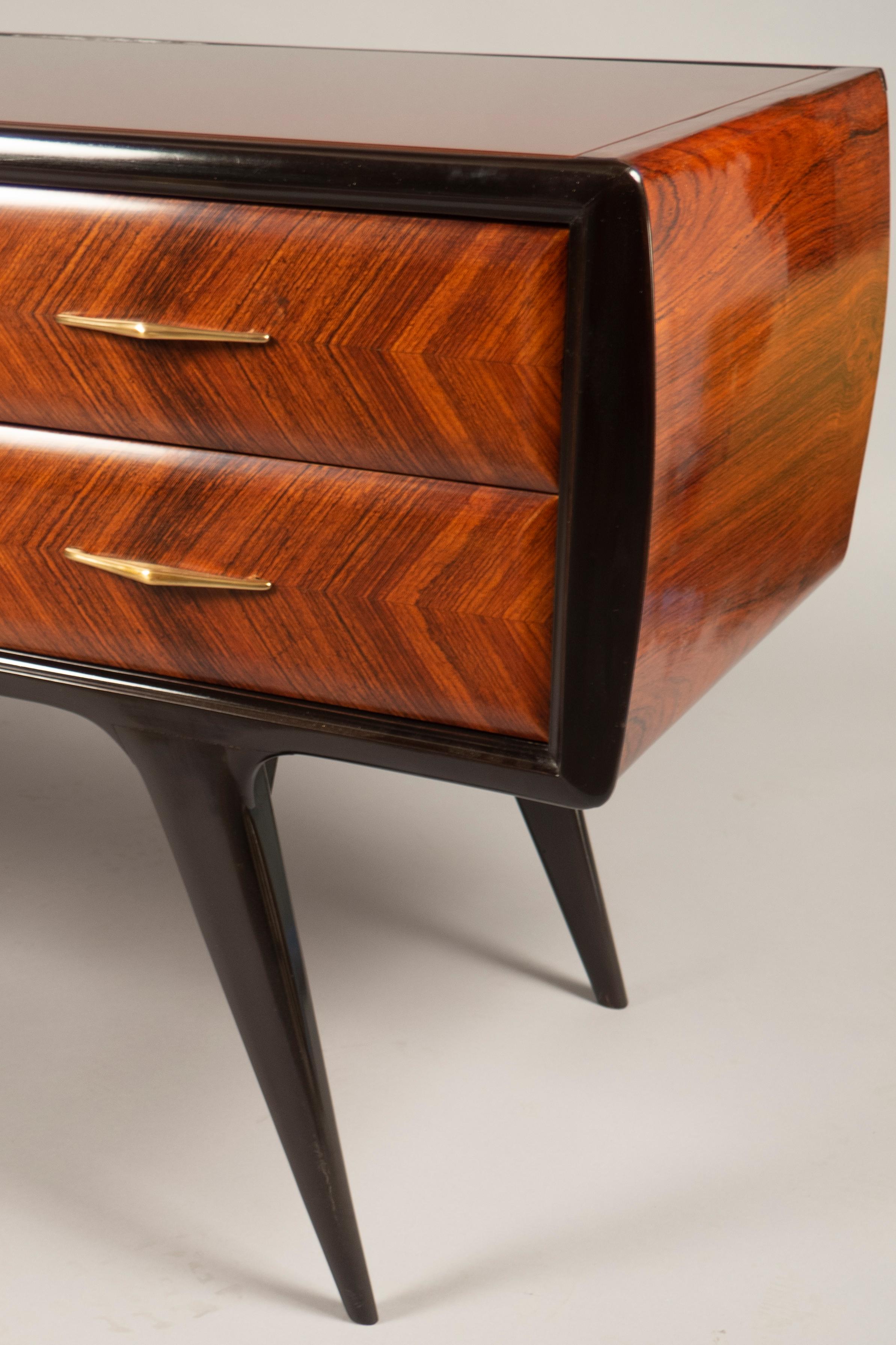 Six-drawer cabinet featuring herringbone wood veneer surrounded by a black wooden frame, raised on tapered legs. The top features a dark maroon glass, which was added by us.
