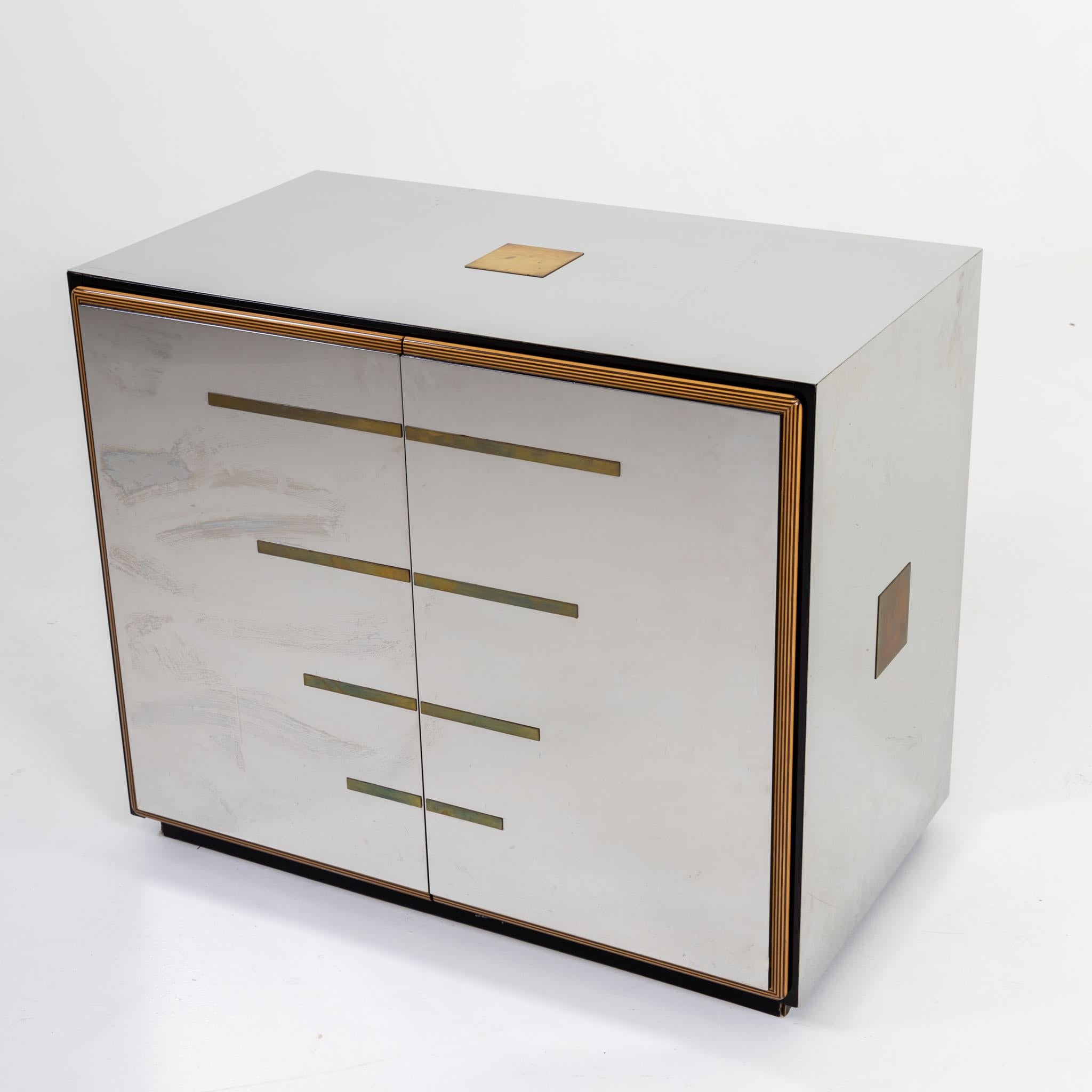 Mirrored sideboard with two doors and polished laminated wood edge and brass applications. Inside it is equipped with shelves and painted black.